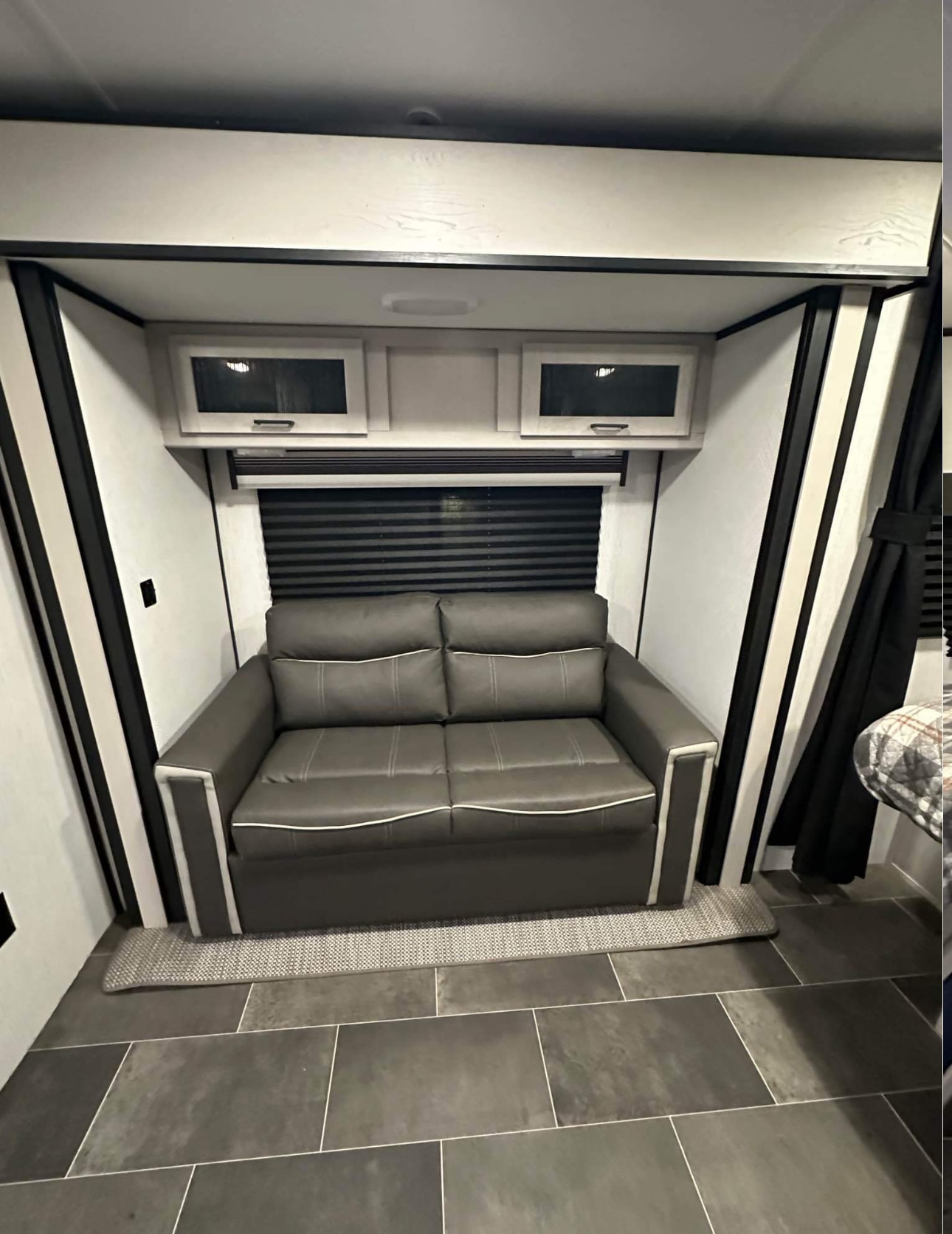 Cozy RV rental interior with a gray sofa, overhead storage cabinets, and dark tile flooring, ideal for a comfortable trip.. Heartland RVs Mallard 2022