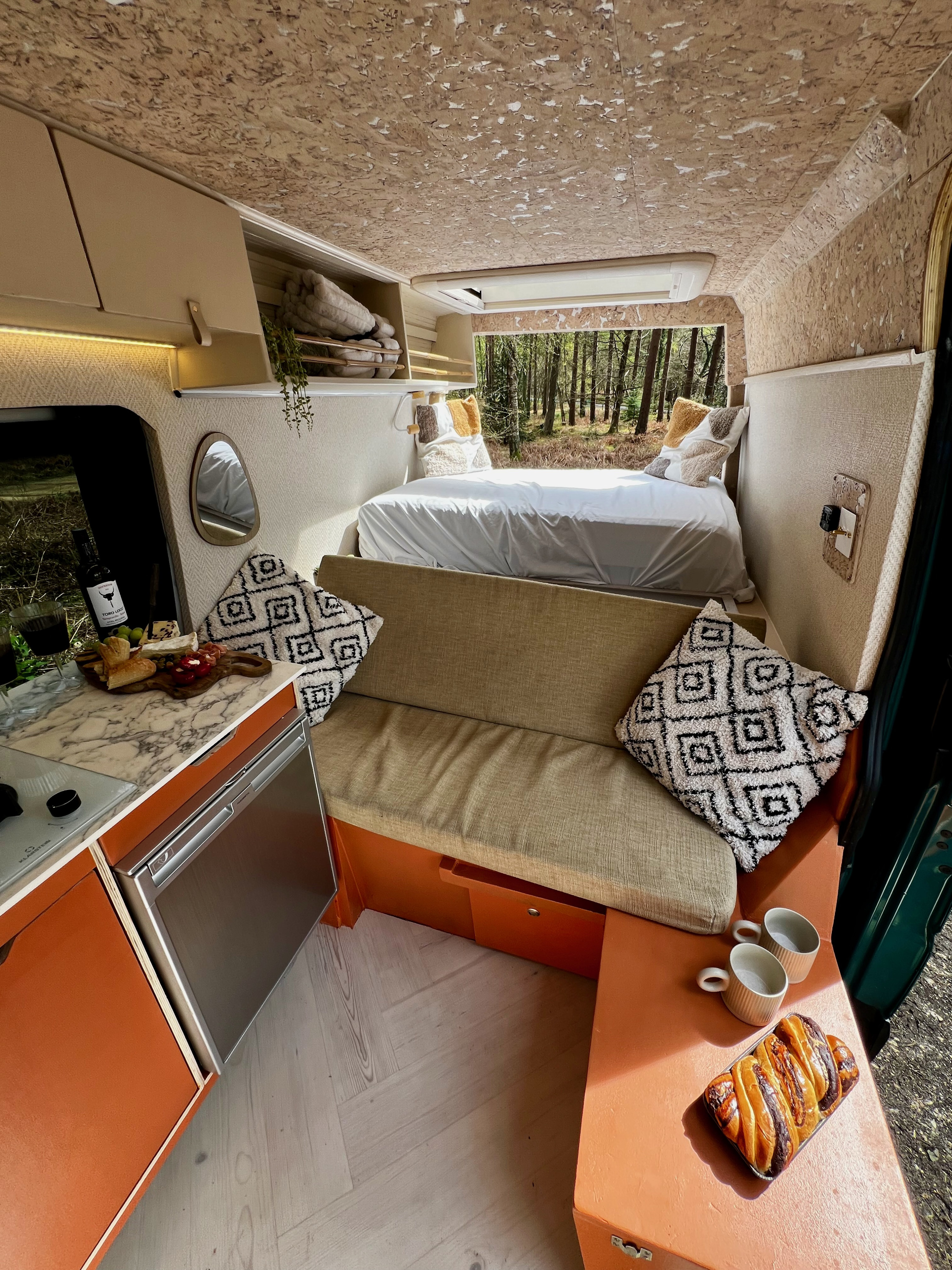 Stylish RV rental interior: cozy bed, compact kitchen with charcuterie, comfy seating, forest views.. Mercedes-Benz Sprinter 2016