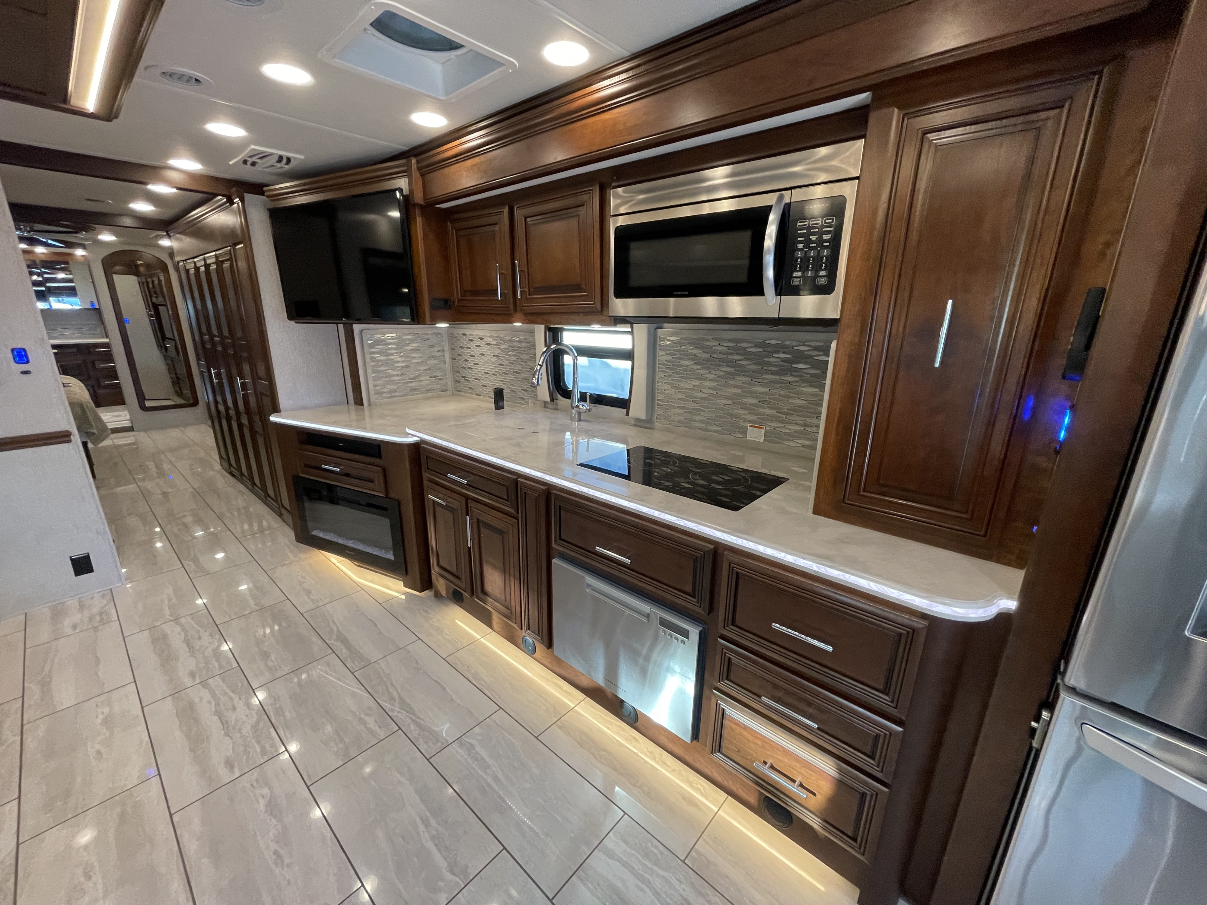 Experience luxury RV rental with this spacious kitchen featuring dark cabinets, light counters, modern appliances, and tiled flooring.. Berkshire XLT 2021
