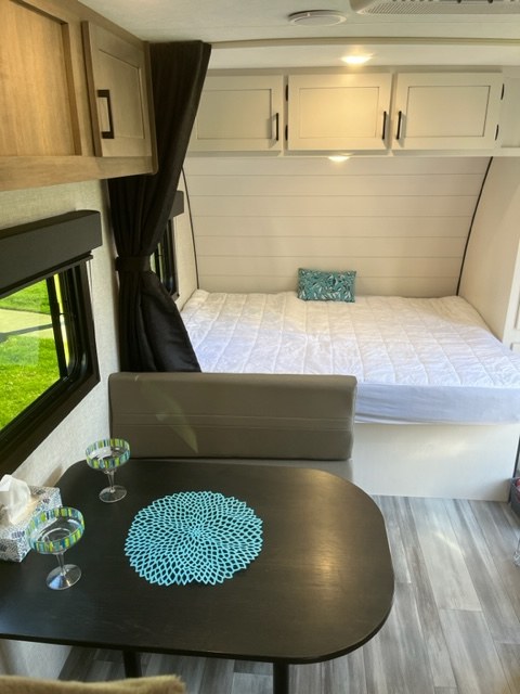 Cozy RV rental interior with bed, dining area, and overhead cabinets, perfect for compact travel.. Starcraft Autumn Ridge 2024