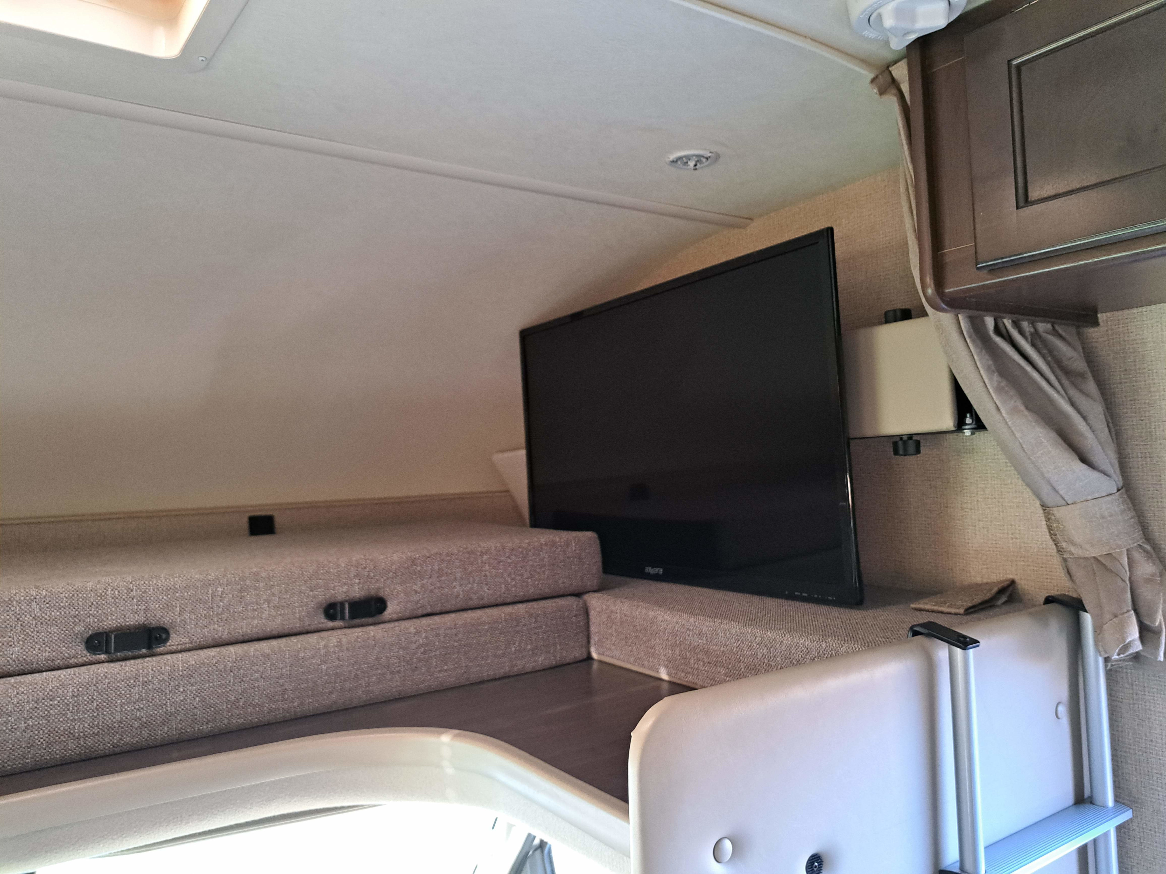 RV rental interior featuring a bunk bed, wall-mounted TV, and overhead cabinet, perfect for a cozy mobile home stay.. Thor Freedom Elite 2019