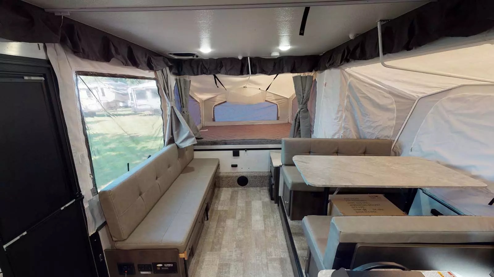 Pop-up RV rental interior featuring a dinette, bench seating, and a large tent-style bed area at the rear.. Forest River Rockwood ESP 2023