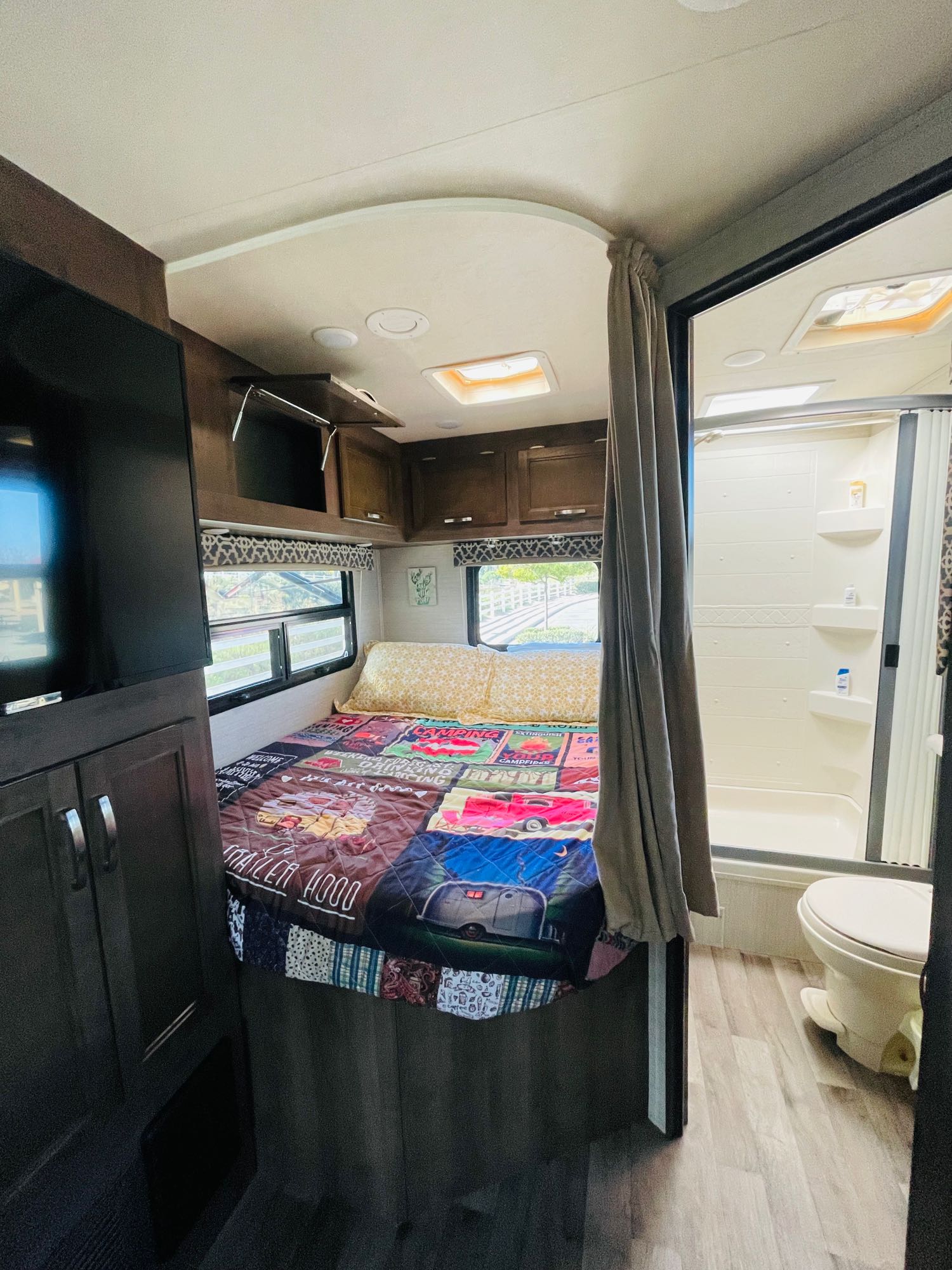 Cozy RV rental interior: bedroom with bed, TV, and en-suite bathroom with shower/toilet. Perfect for travel & camping.. Jayco Redhawk 2019