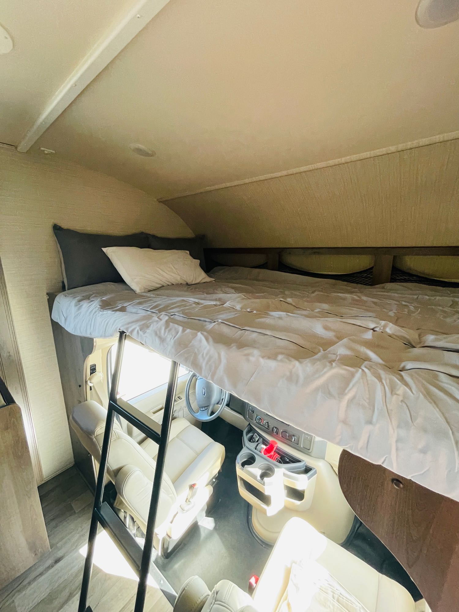 RV rental interior showing a comfortable over-cab bunk bed with ladder above the driver and passenger seats.. Jayco Redhawk 2019