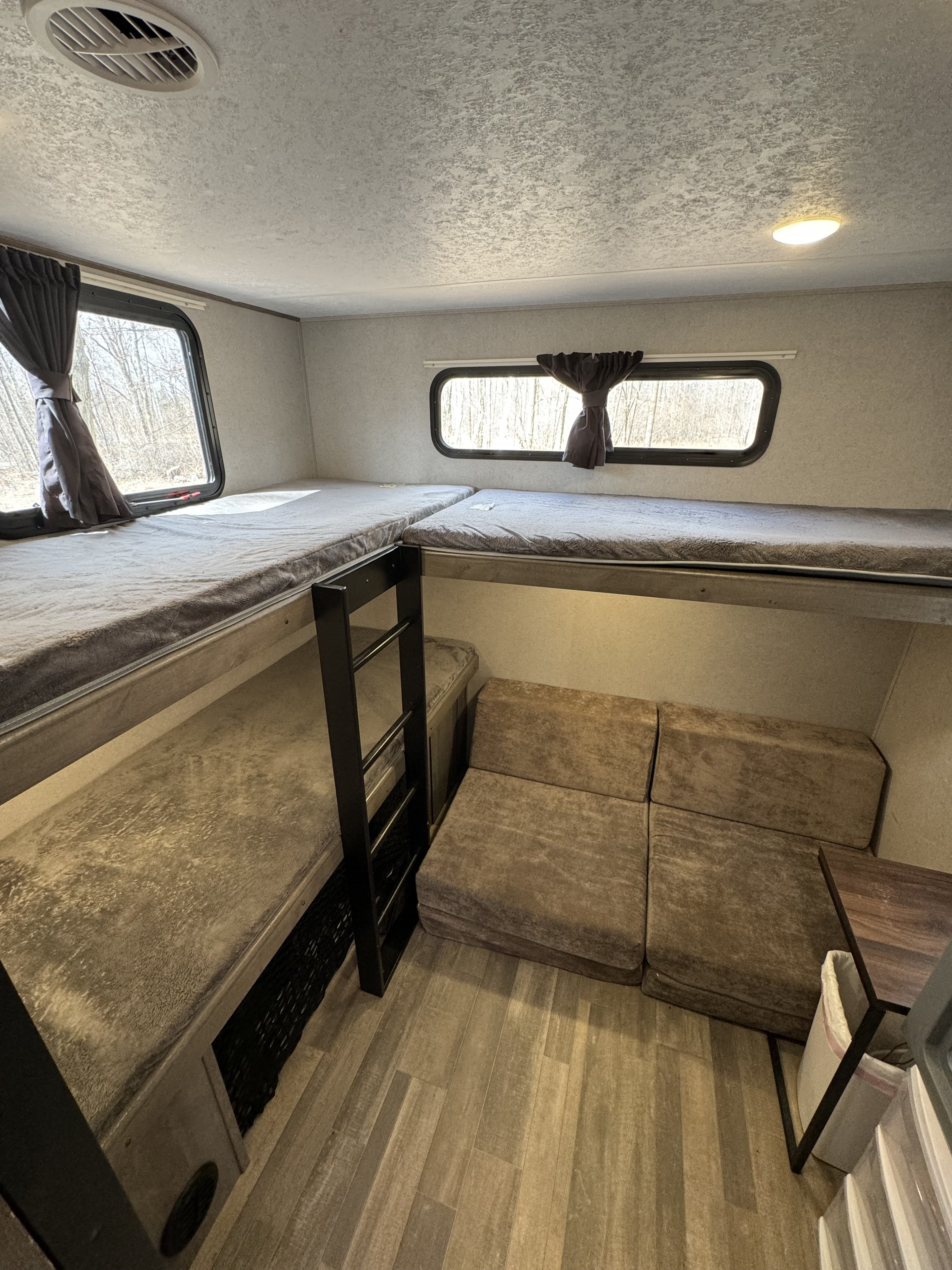 Spacious RV rental interior with comfortable bunk beds, a modular lounge, and bright windows for your next adventure.. Forest River Vibe 2021