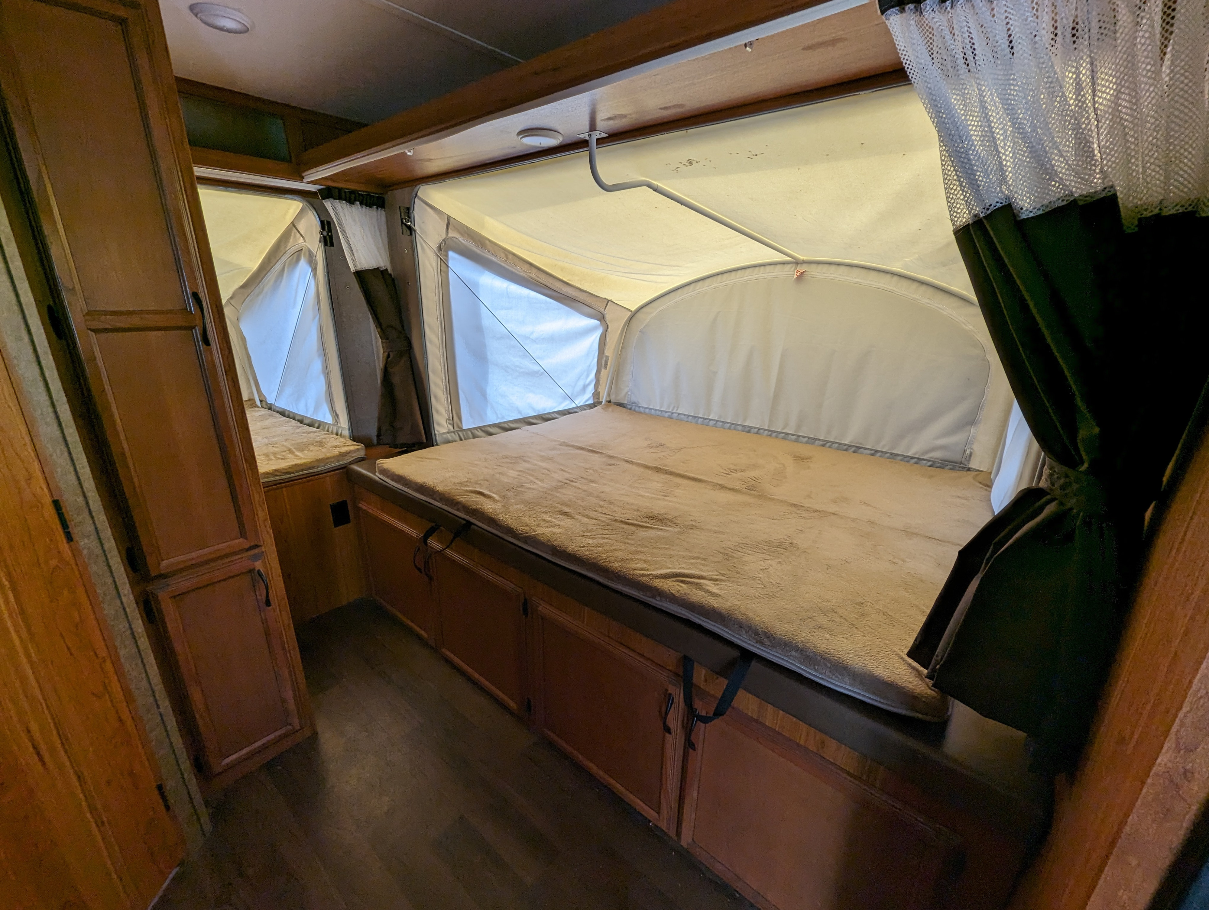 Interior of an RV rental showing two pop-out beds with soft blankets, wood cabinetry, and bright tent windows.. Starcraft Travel Star 2016