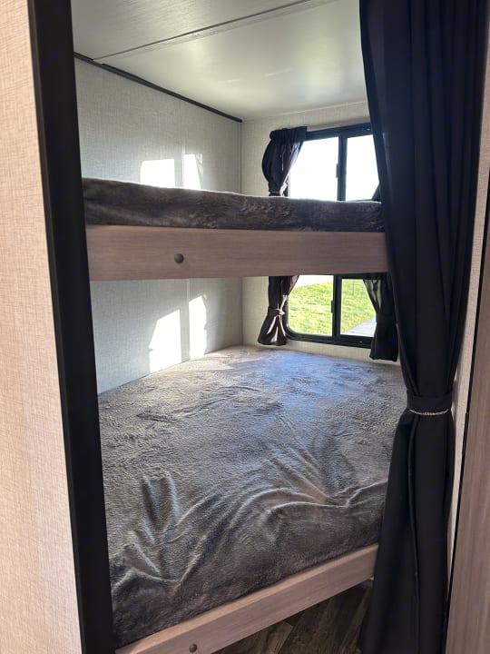 Inside an RV rental: two comfortable bunk beds with grey blankets and windows for natural light. Ideal for families.. Crossroads Sunset Trail Super Lite 2022