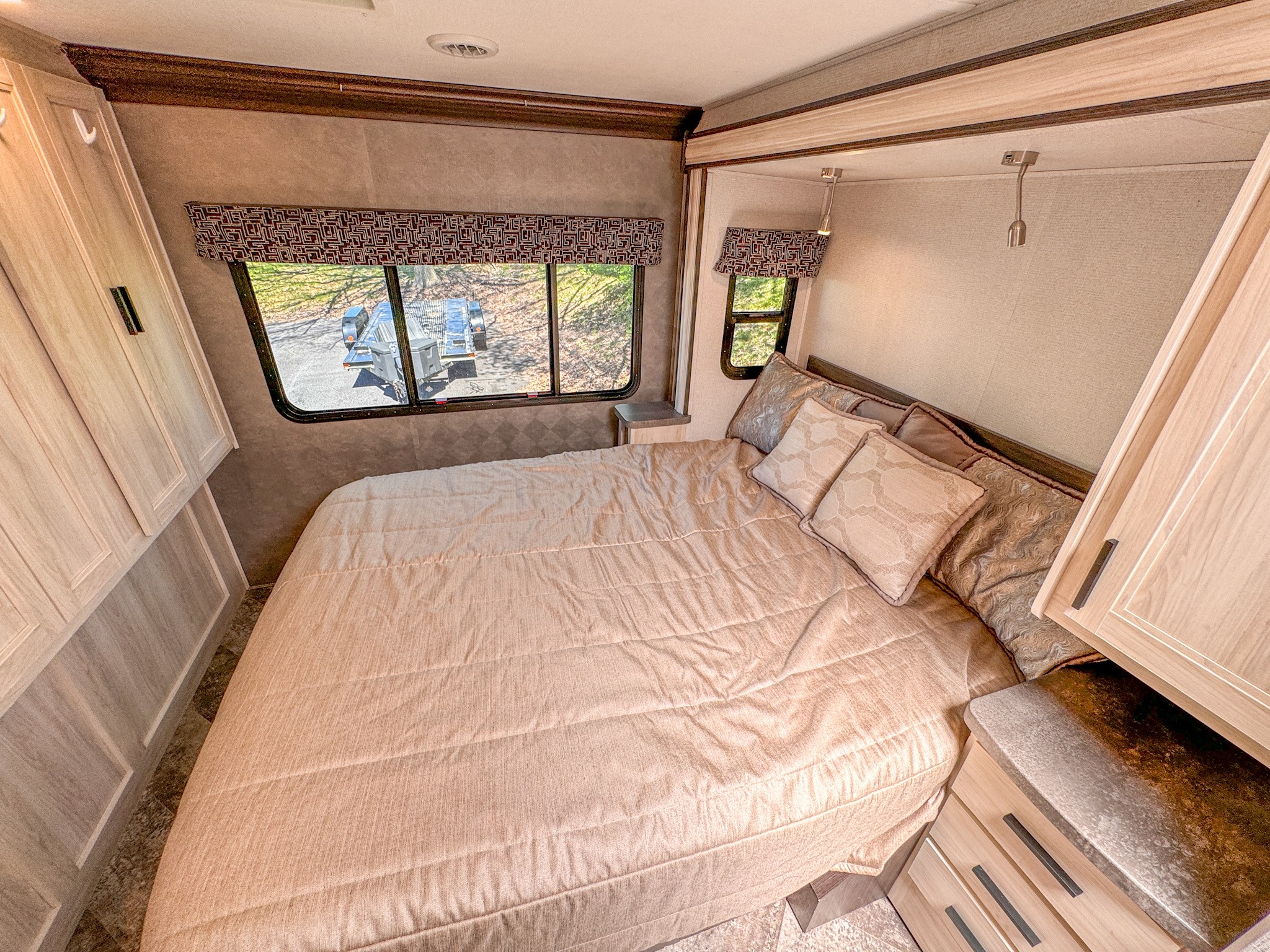 Cozy RV rental bedroom with a large bed, multiple windows, and light wood cabinets, perfect for a comfortable stay.. Forest River Sunseeker 2021