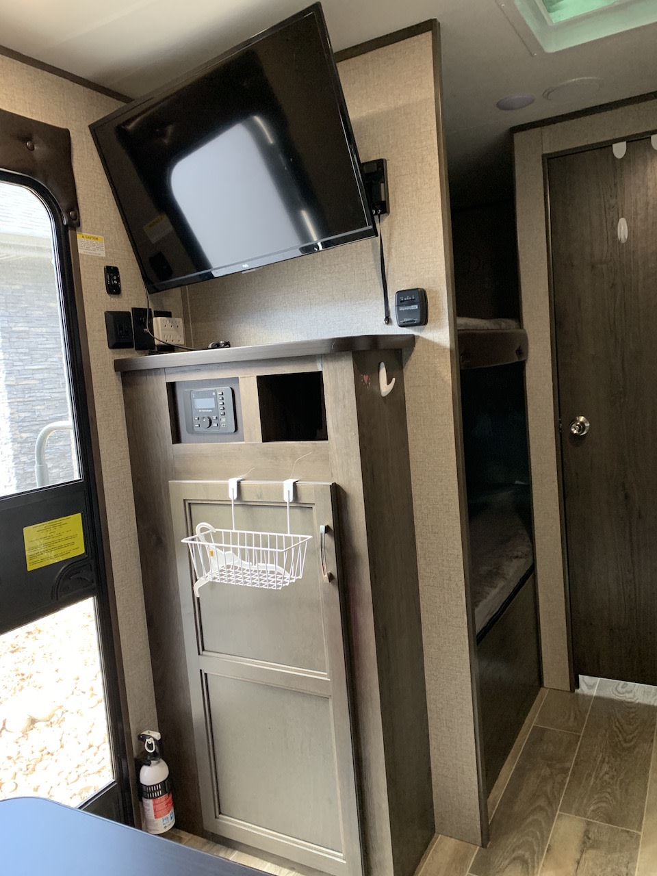 RV rental interior featuring a mounted TV, bunk beds, control panel, and storage basket.. Jayco 154BH 2021