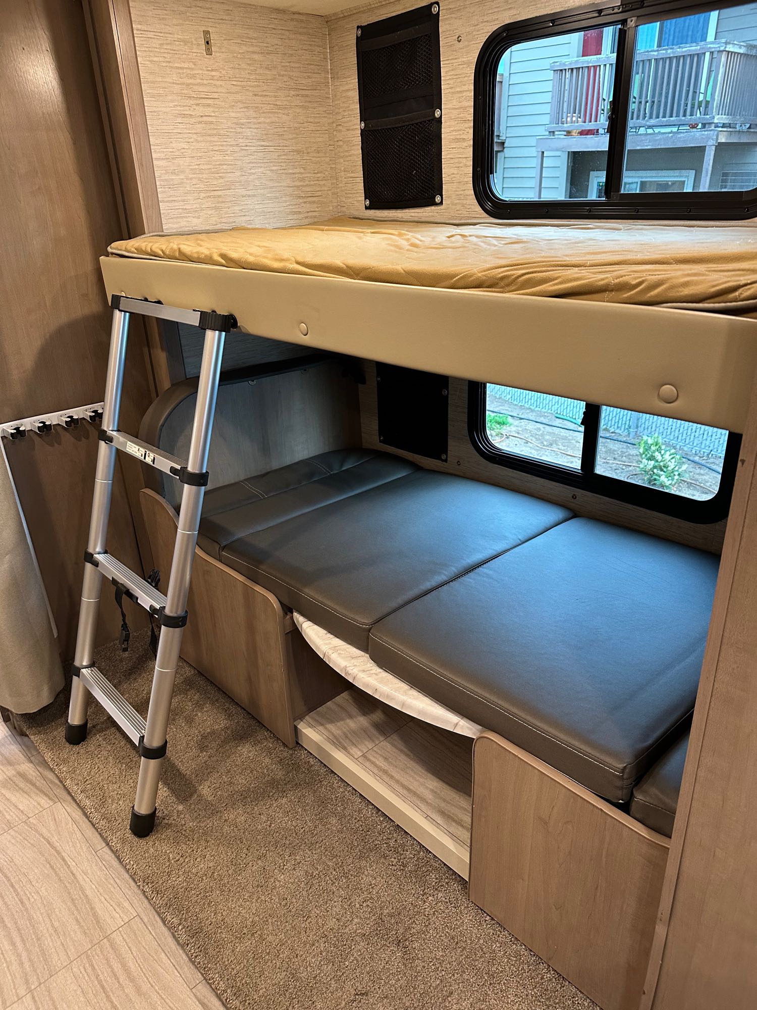 RV rental interior: Bunk beds with ladder, convertible lower bed/seating, and windows. Cozy camper layout.. Thor Coleman 2022