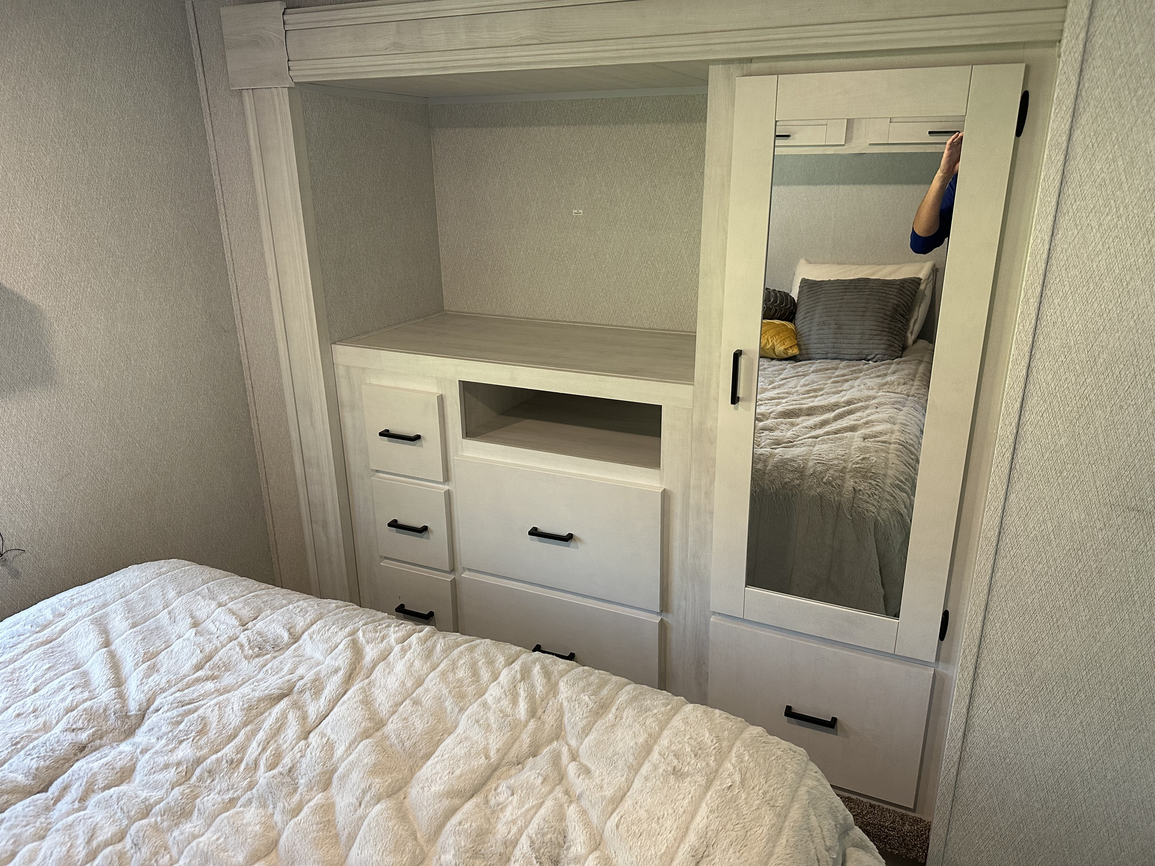 Discover this cozy RV rental bedroom. It features a soft bed, built-in dresser, and mirrored wardrobe for storage.. Forest River 3100FB 2024