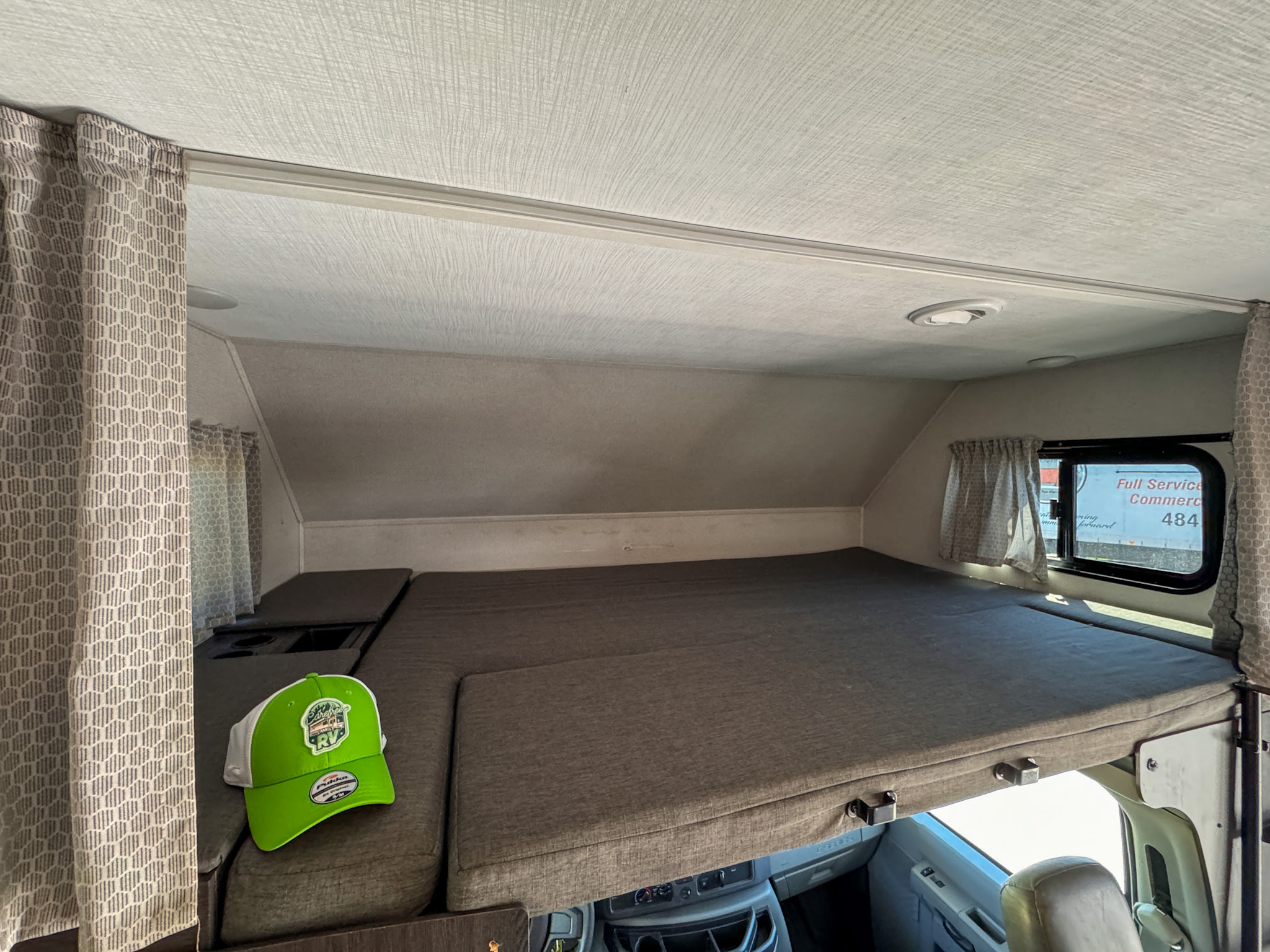 Interior of an RV rental, showcasing the spacious cab-over bunk sleeping area with a large mattress and window.. Forest River Sunseeker 2021