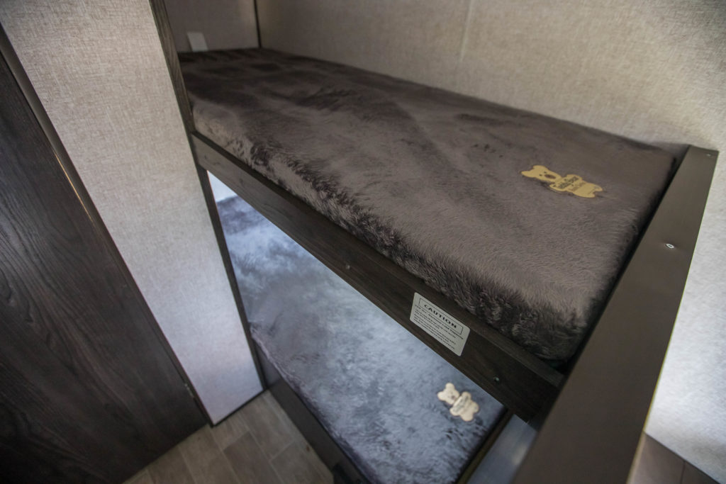 Inside an RV rental: Two stacked, cozy pet bunks featuring soft grey beds and bone toys. Perfect for your furry travel companions.. Keystone RV Lantane 2017