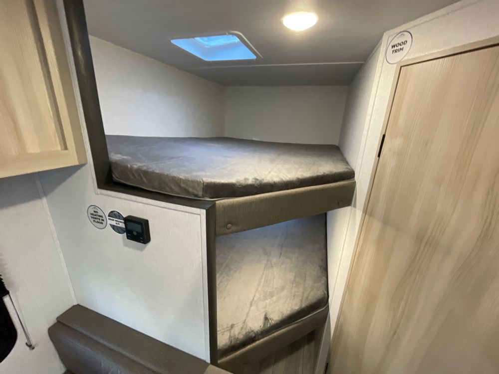 Interior of an RV rental: Compact sleeping area with stacked bunk beds, skylight, and control panel. Ideal for campers.. East to West SILVER LAKE LE 17BHLE 2024