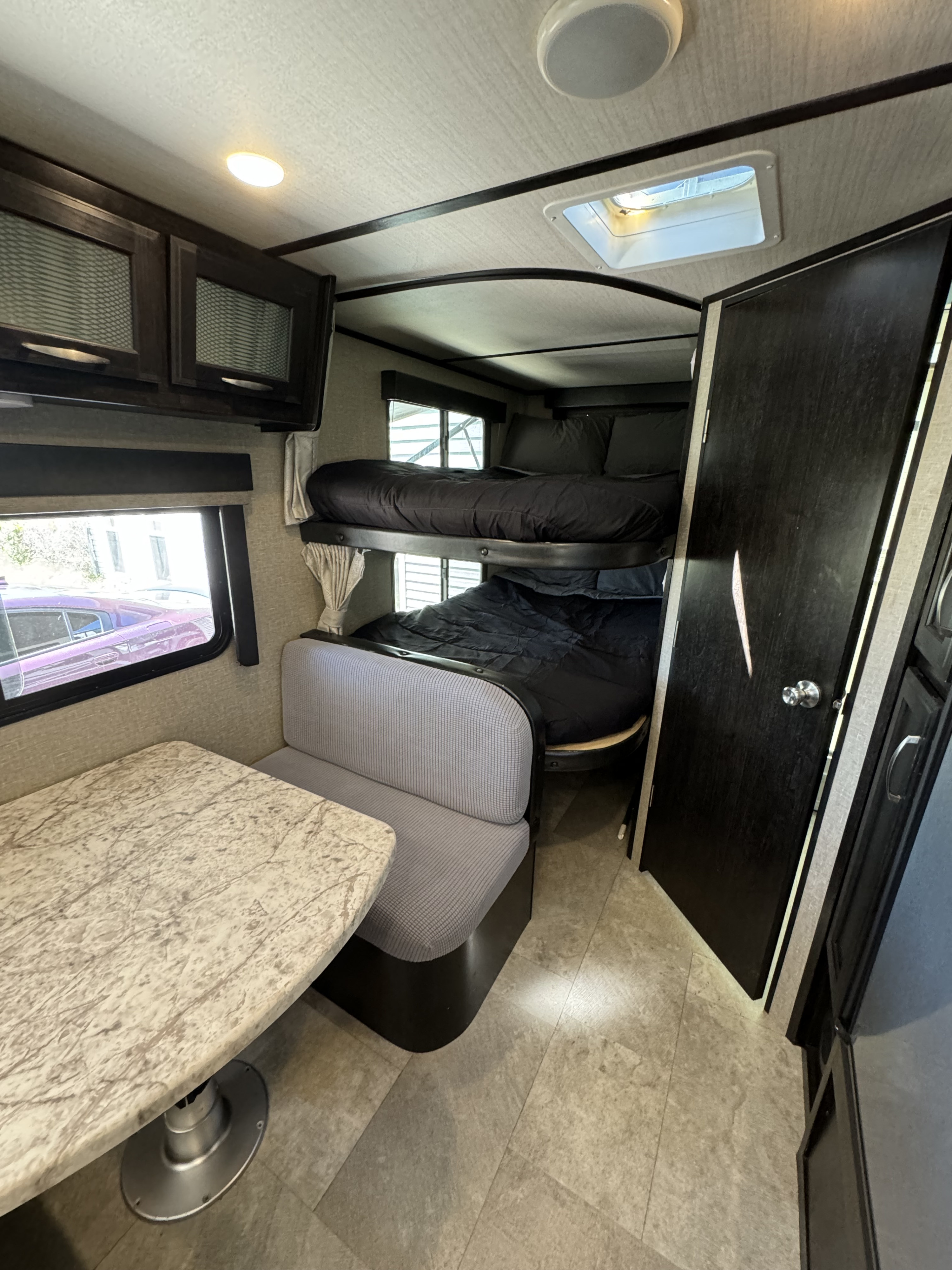 RV rental interior with bunk beds, a dinette, and overhead cabinets. Ideal for comfortable family travel.. Grand Design Imagine 2019