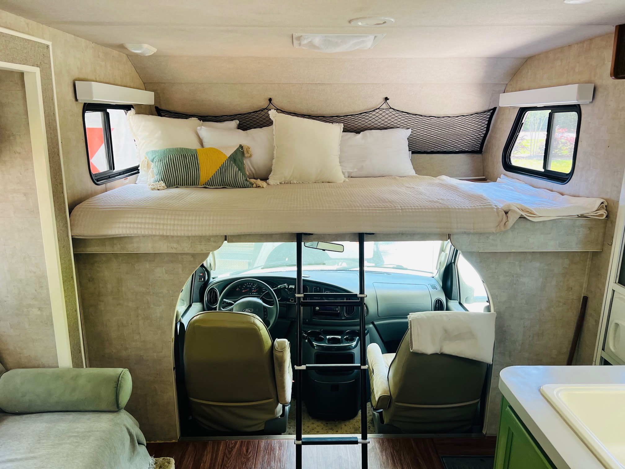 An RV rental's cozy interior, featuring a well-appointed cab-over bed and the vehicle's front seats.. Tioga Tioga Motorhome 2006