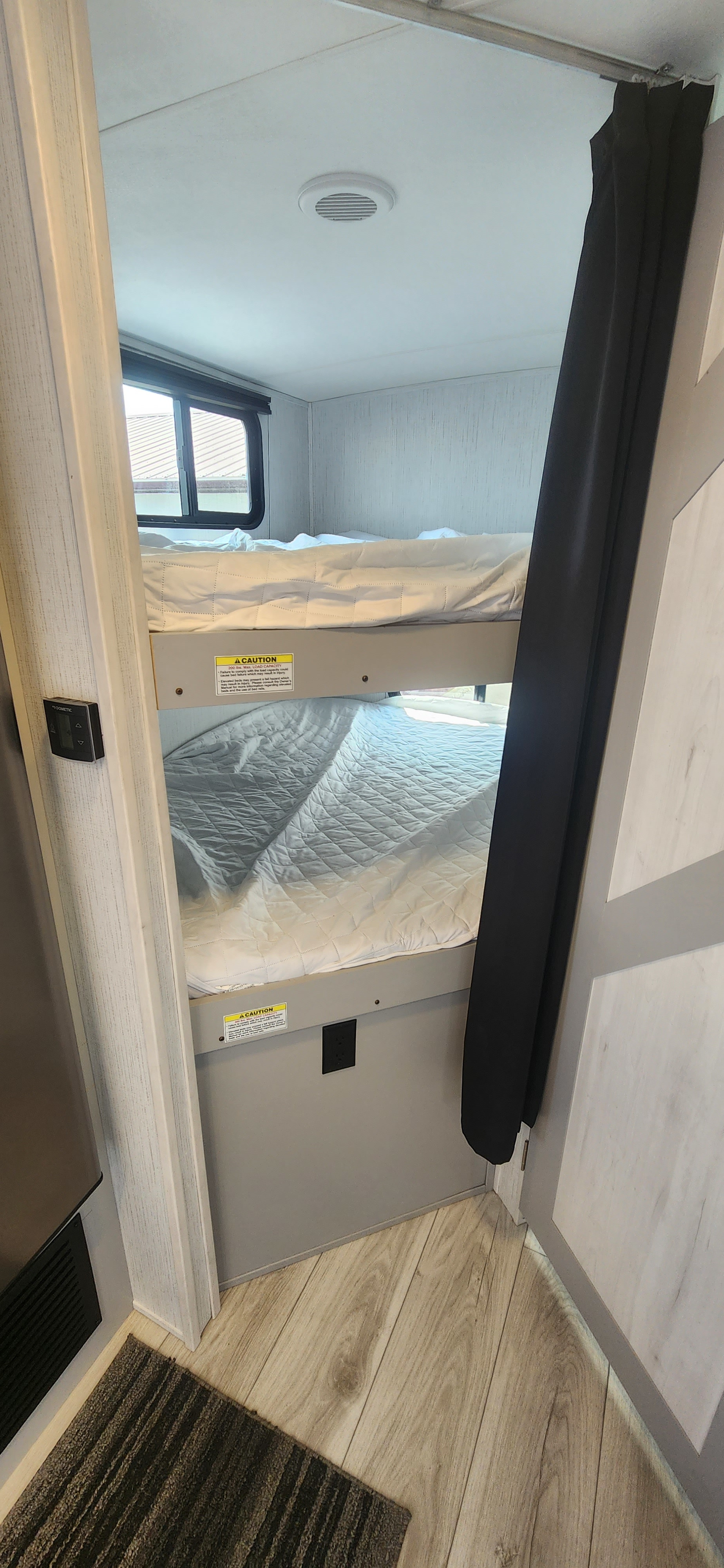 Inside an RV rental: bright bunk beds with window, outlet, and climate control for family comfort on your travels.. Heartland North Trail 2022