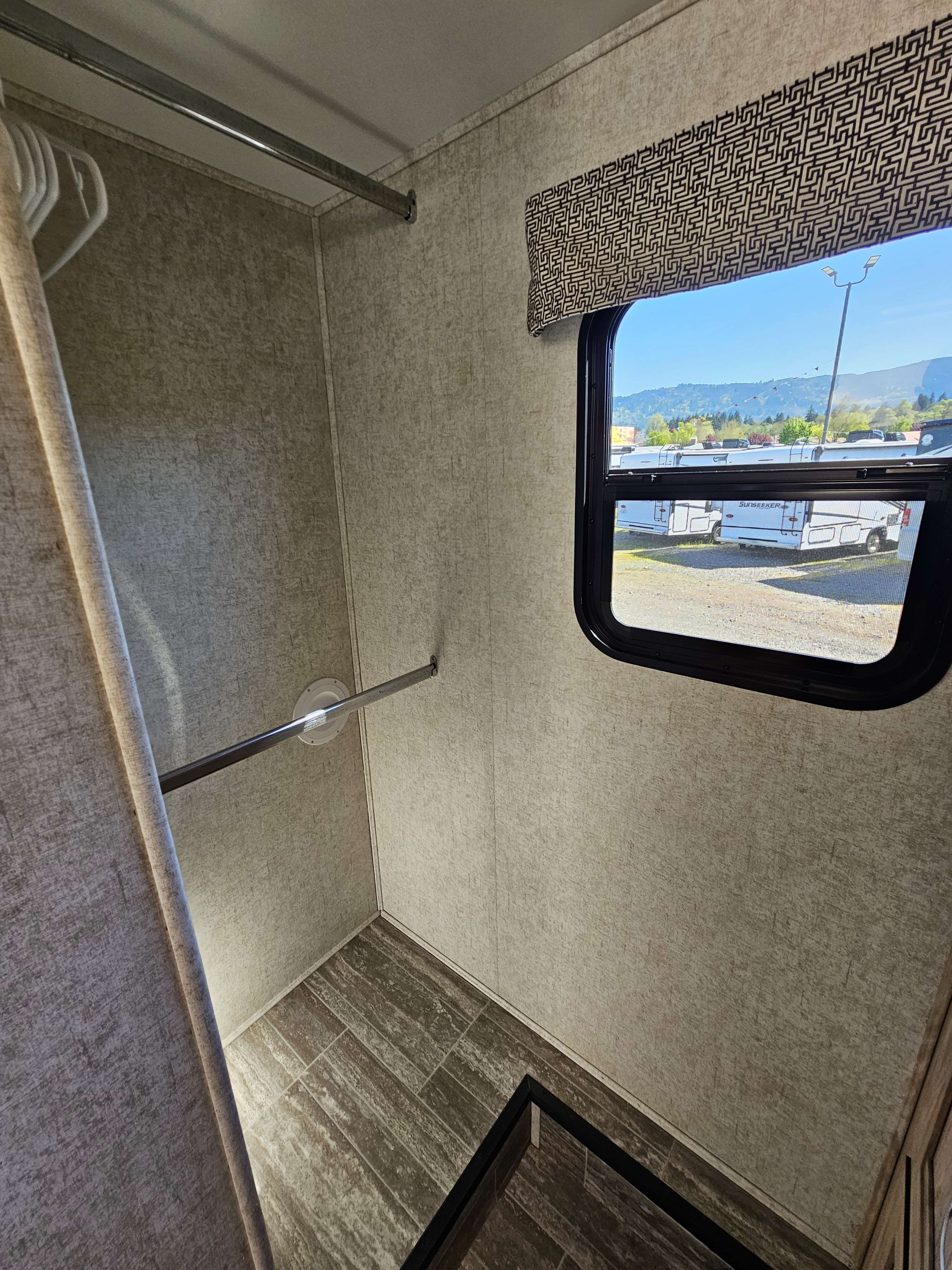 Spacious RV rental interior features a closet with hanging rods, tile flooring, and a window view of a sunny RV lot.. Forester 2421MS 2019