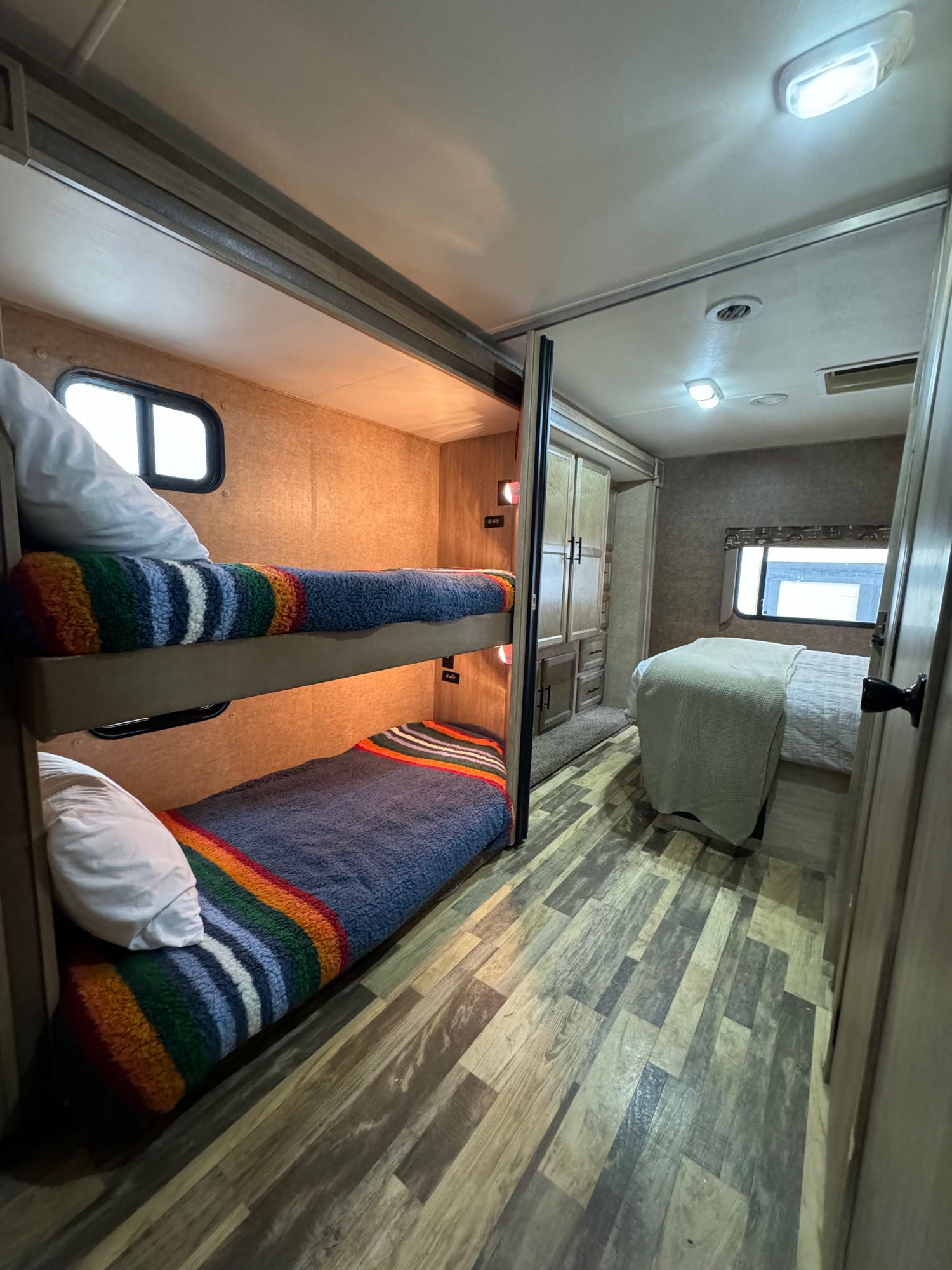 RV rental interior features cozy bunk beds on the left and a main bedroom on the right, perfect for family travel.. Forest River Coachmen Freelander 2015