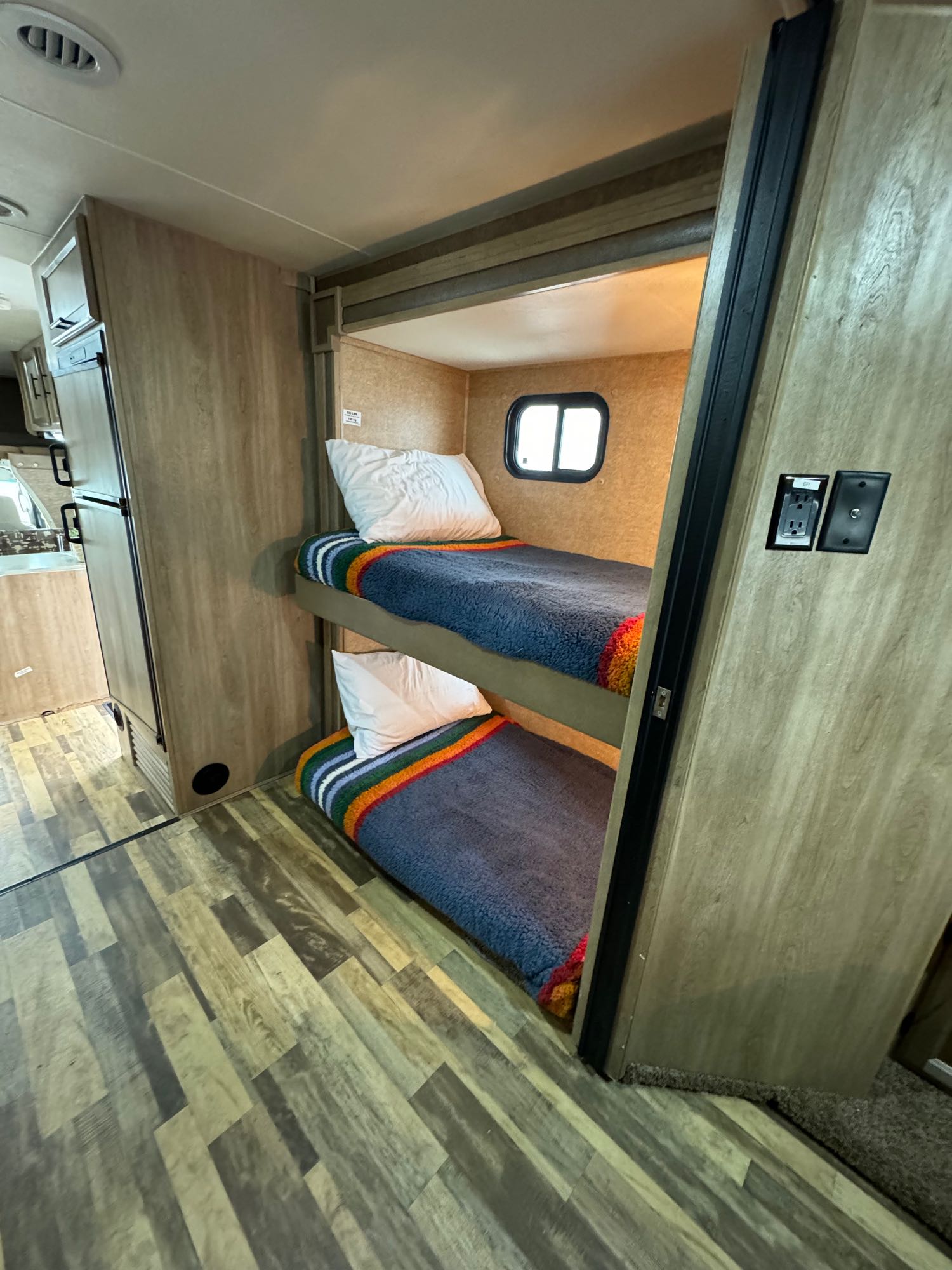 Cozy RV rental interior featuring bunk beds, a compact fridge, and wood-look flooring, perfect for family travel.. Forest River Coachmen Freelander 2015