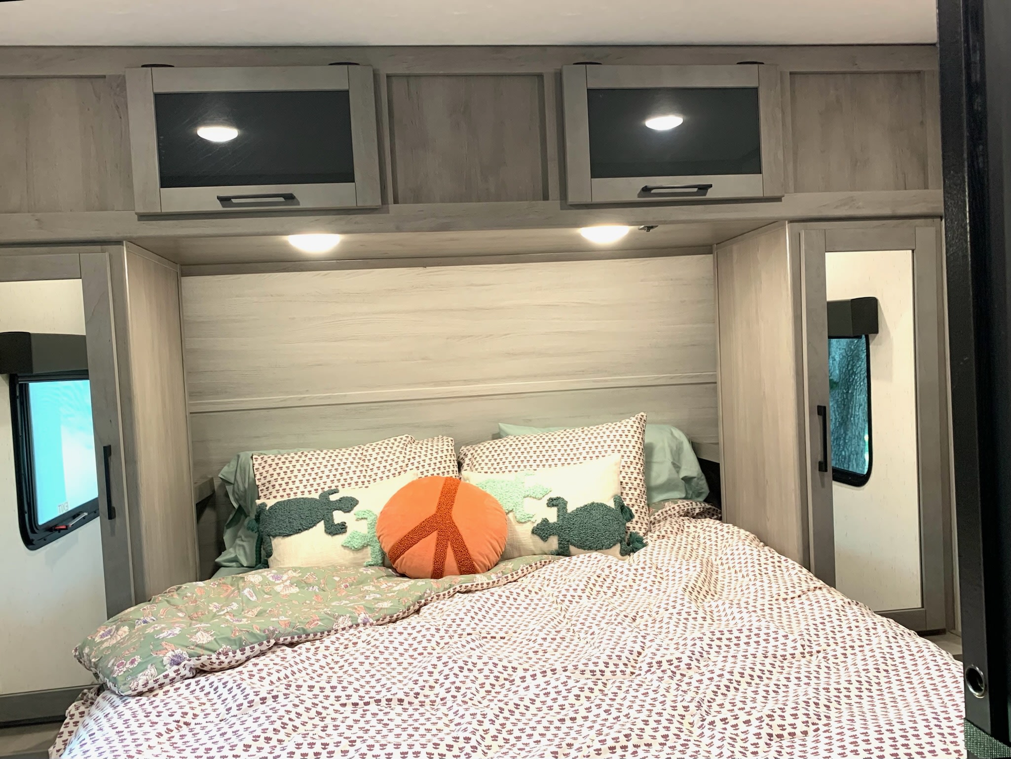 Cozy RV rental bedroom featuring overhead cabinets, under-cabinet lighting, and unique decorative pillows. Ideal for your travels.. Dutchmen Kodiak Ultra Lite 2022