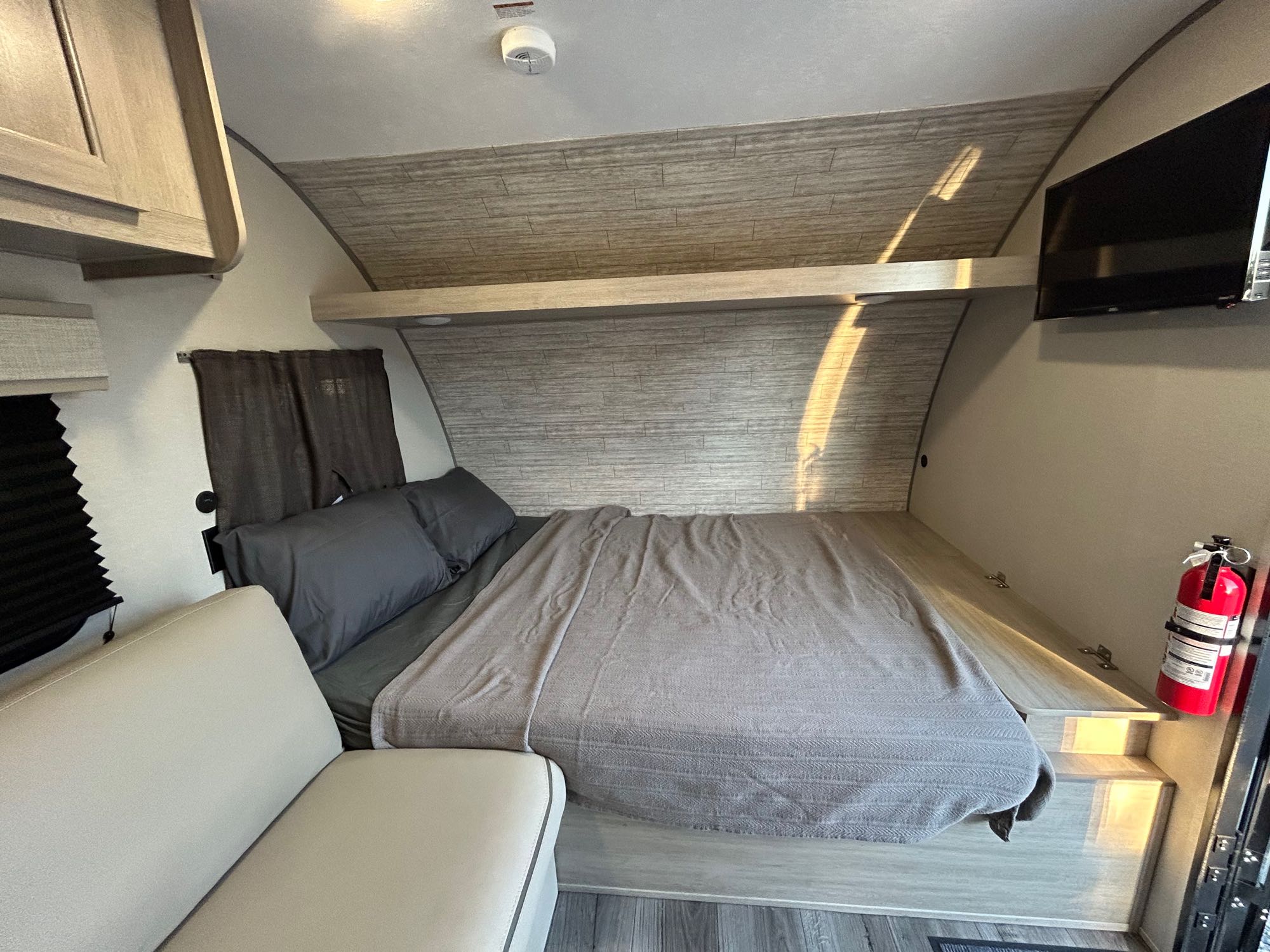 This RV rental bedroom offers a cozy bed, overhead storage, and TV, ideal for comfortable travel.. Forest River Coachmen Catalina Summit Series 2024