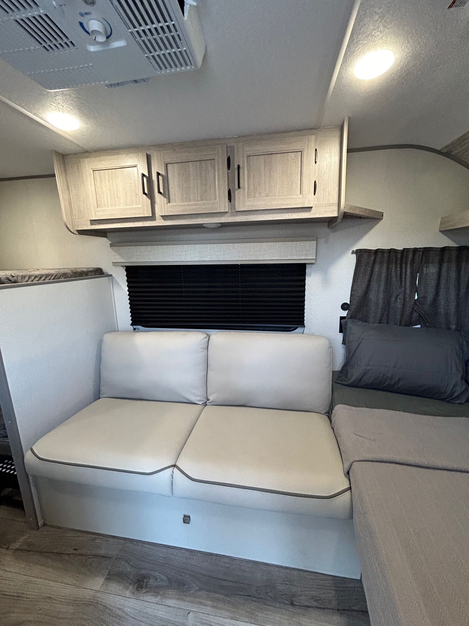 Cozy RV rental interior with light couch, overhead cabinets, and a bed, showcasing a compact living space.. Forest River Coachmen Catalina Summit Series 2024