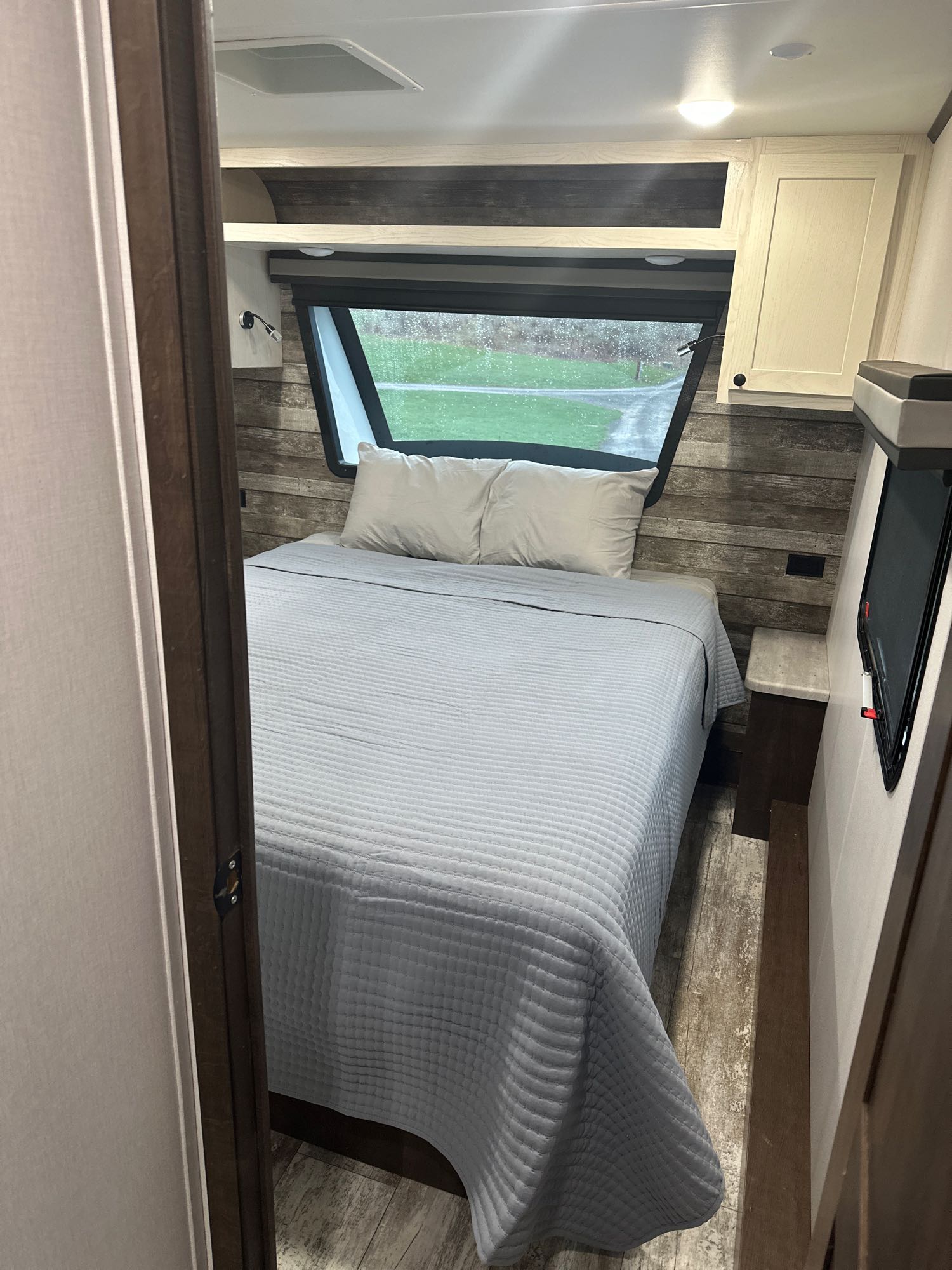 Cozy RV rental bedroom with bed, large window, overhead cabinets & TV. Ideal for travel and comfortable stays.. Forest River Nitro Xlr 2021