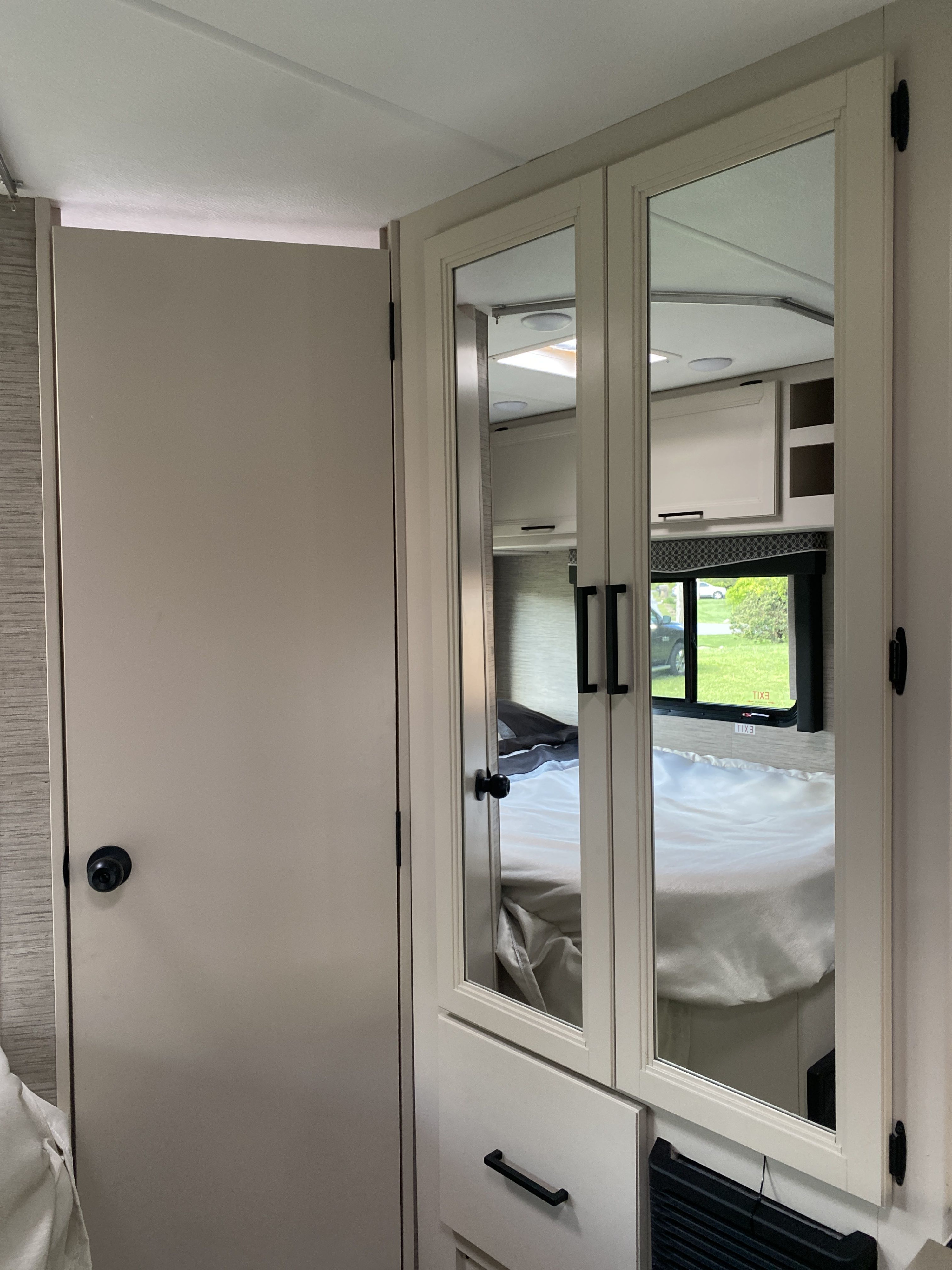 Step inside this cozy RV rental! Mirrored wardrobe doors reflect the compact bedroom area and bright interior. Perfect for your next adventure.. Ford F350 22E MC 2023