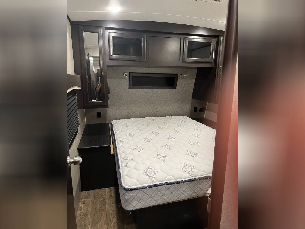 Cozy RV rental bedroom featuring a mattress, overhead cabinets, and nightstand, providing a comfortable space.. Jayco Eagle HT 2019