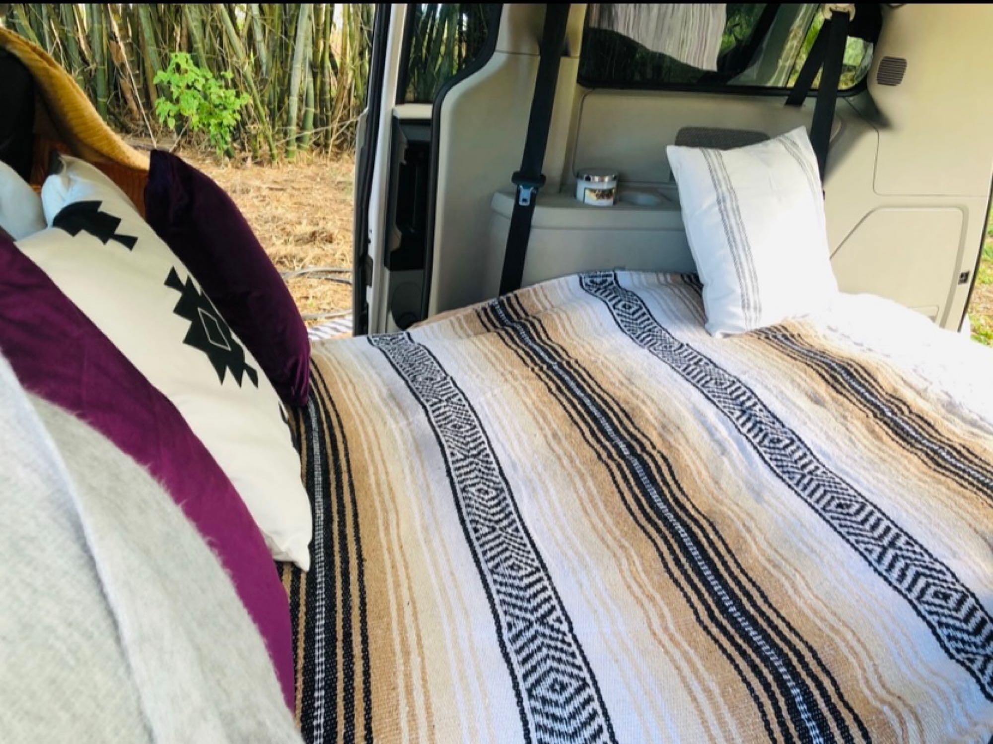 Comfortable RV rental interior with a bed, blankets, pillows, and a nature view. Ideal for road trip camping.. Dodge Other 2013