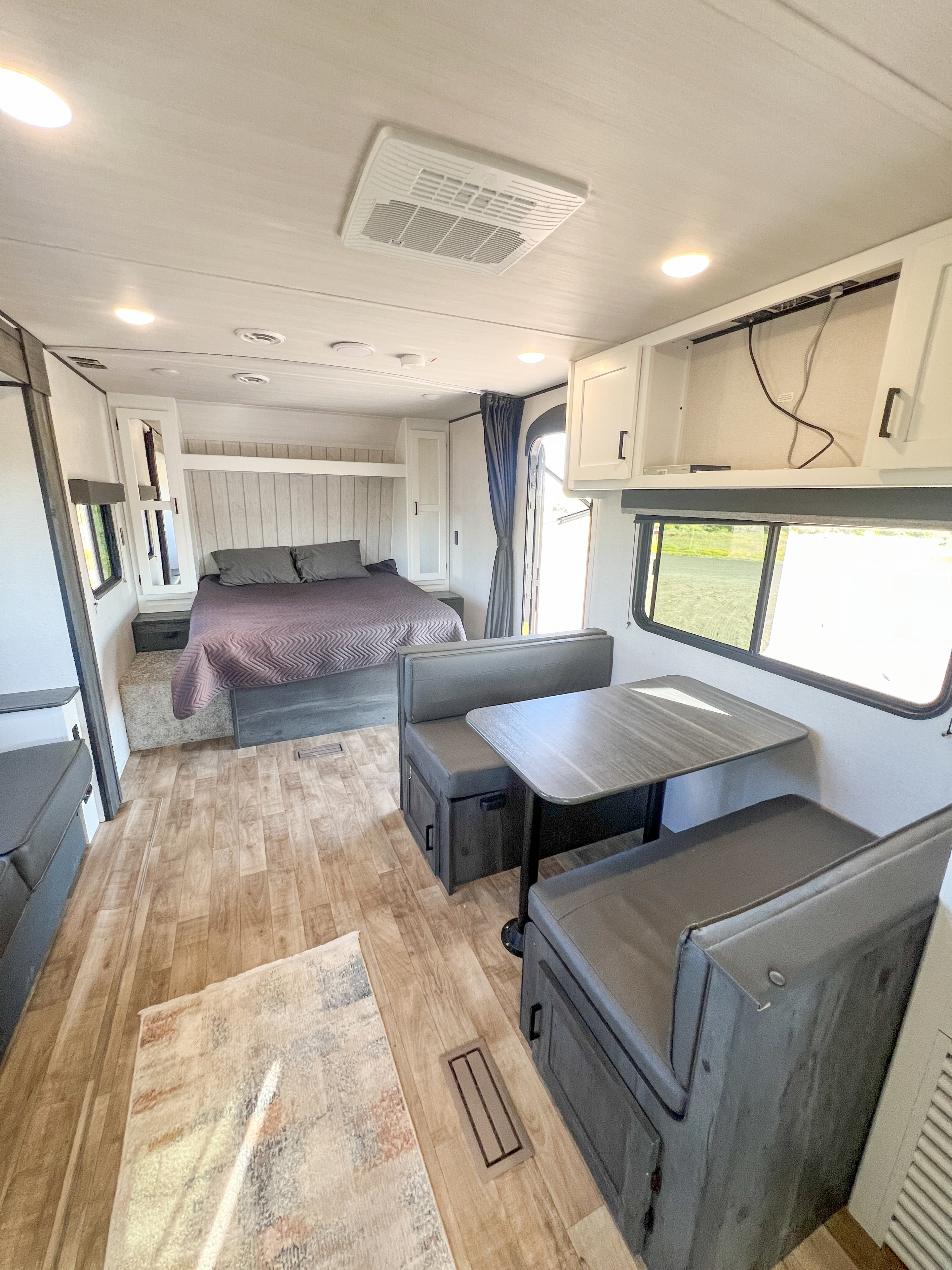 Bright RV rental interior with bedroom, dinette, and overhead cabinets. Experience comfy travel in this mobile home.. Keystone RV Hideout 2023