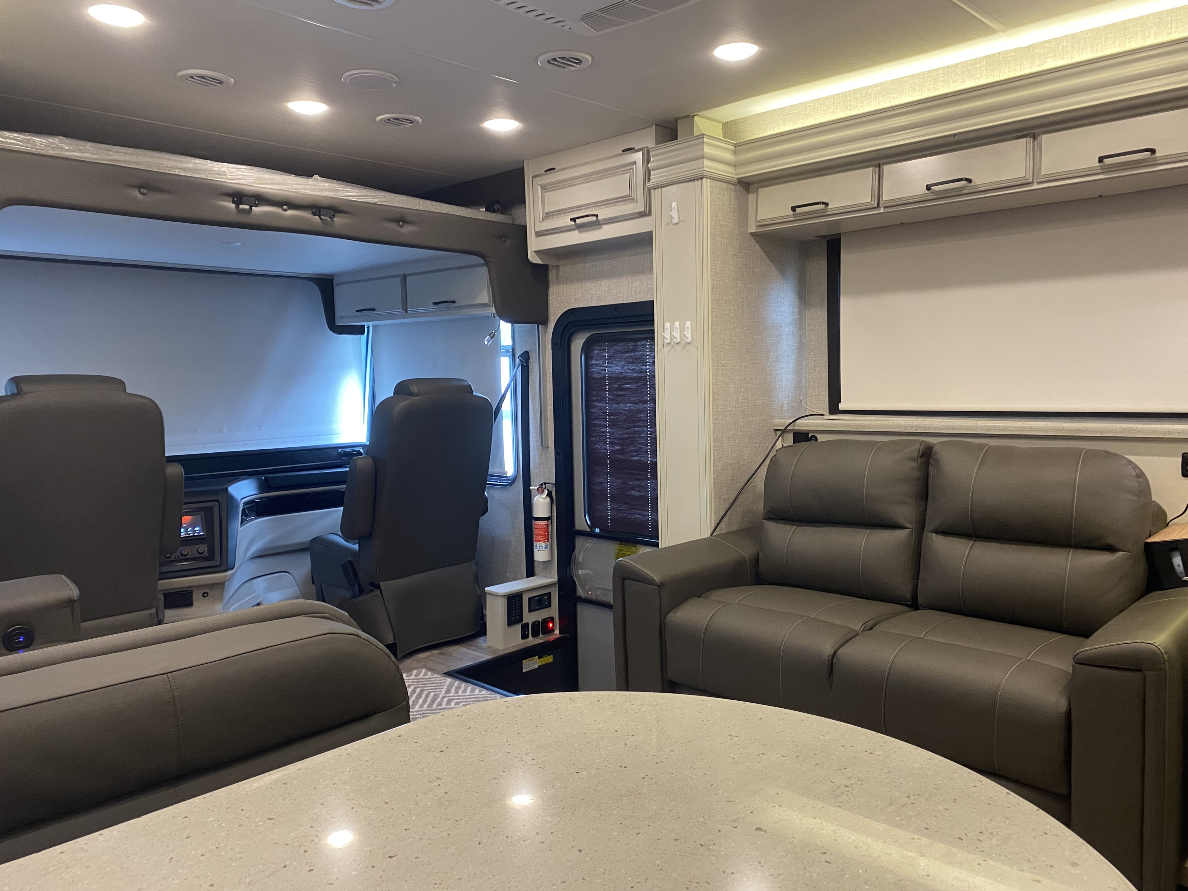 Inside this RV rental: spacious living area with a sofa, comfortable cockpit seats, and a projector screen for entertainment.. Jayco Precept 2023