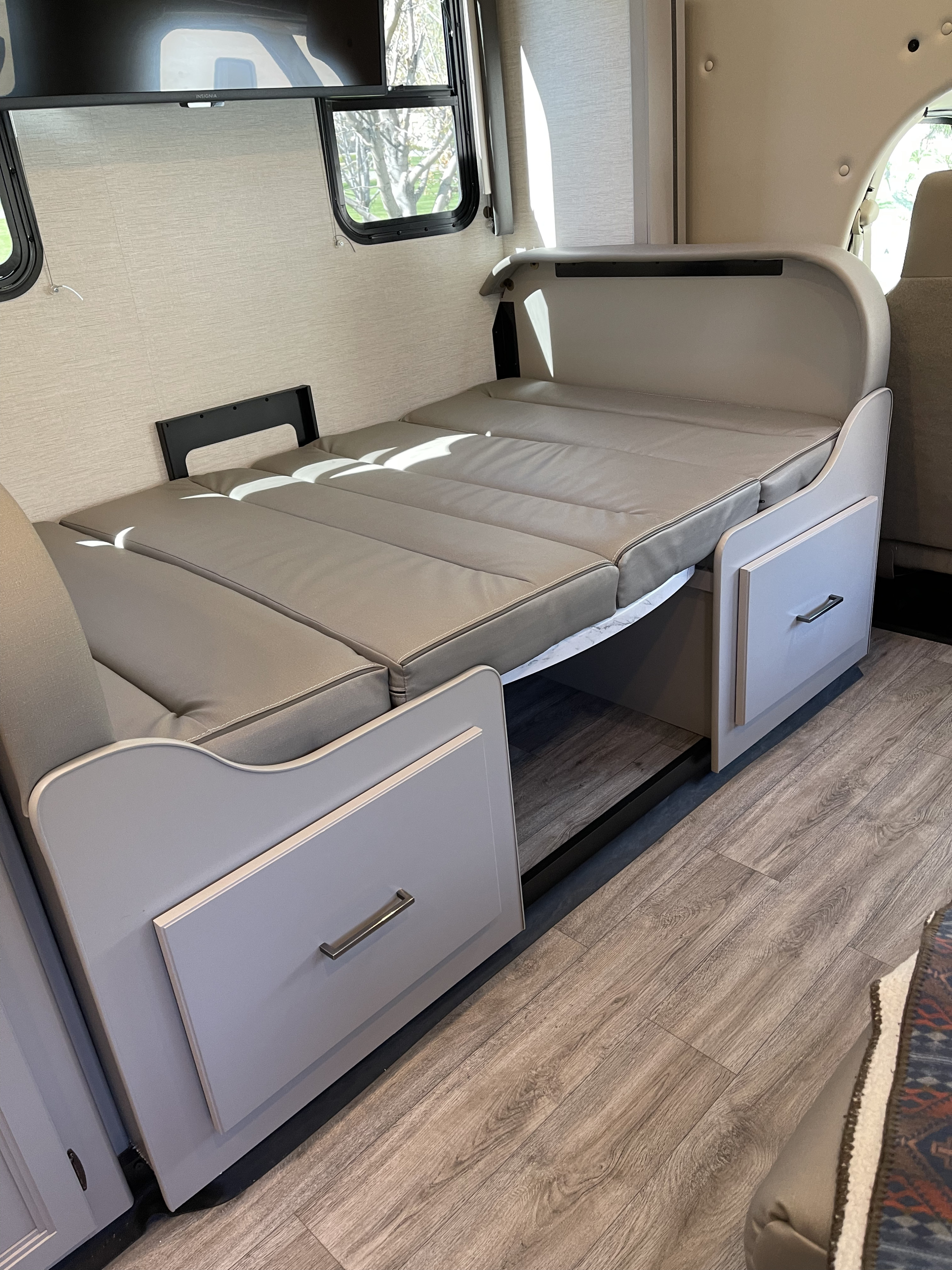RV rental interior showing a light grey sofa converting to a bed, with convenient under-seat storage drawers.. Thor Coleman 2024