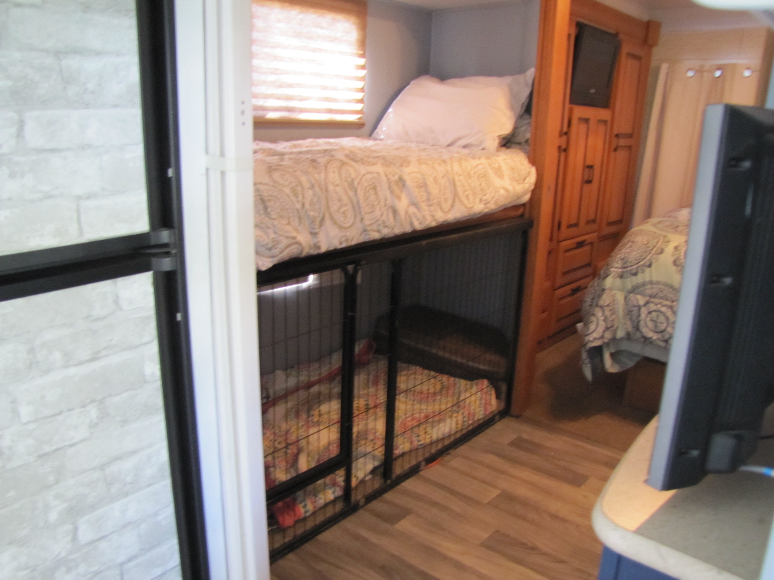Cozy RV rental interior with a bunk bed over a pet crate, another bed, and storage cabinetry.. Forest River Sunseeker 2011