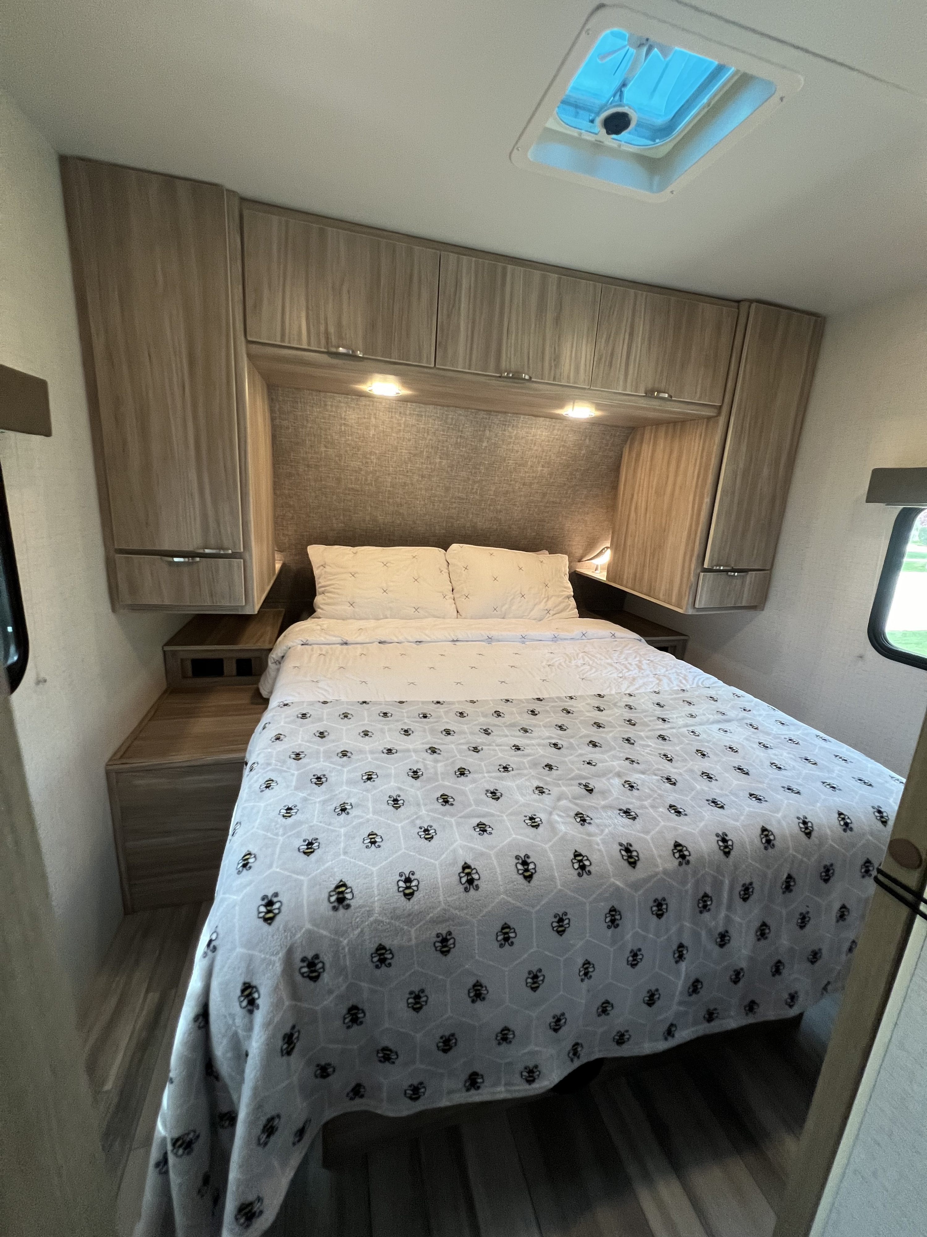 Cozy RV rental bedroom with a queen bed, honeycomb blanket, overhead storage, and skylight. Perfect for trips.. Winnebago 2301BHS 2022