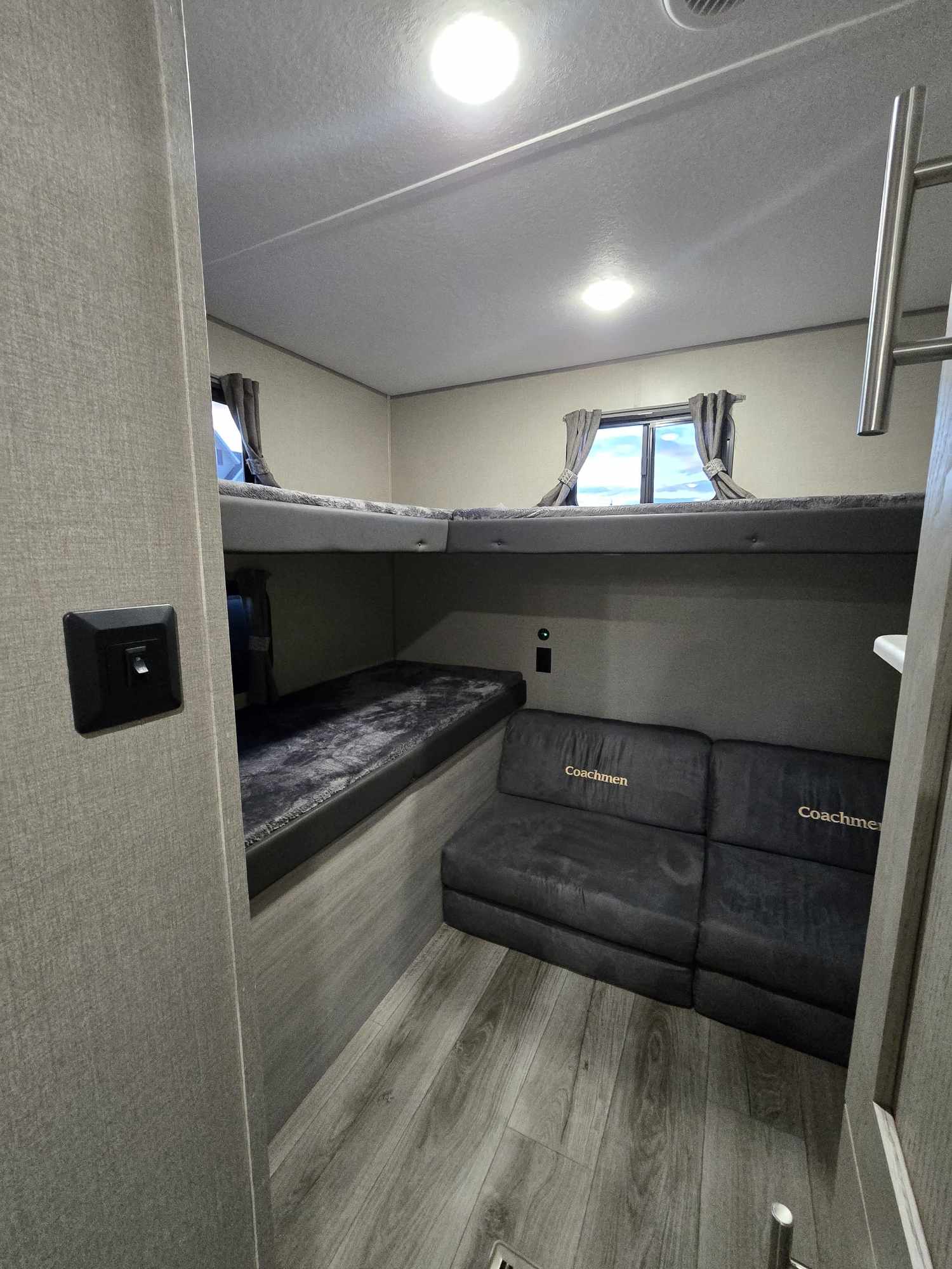 RV rental interior with bunk beds, a Coachmen sofa, and wood-look flooring, under bright lights.. Coachmen Catalina Legacy 293QBCK 2023