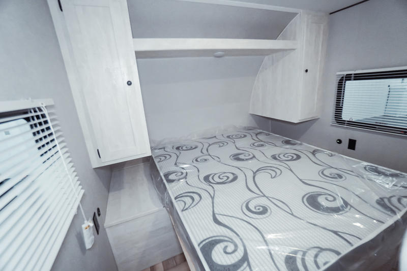 RV rental bedroom with new mattress, overhead cabinets, and blinds, ready for a cozy trip.. Gulf Stream Grand River 2023