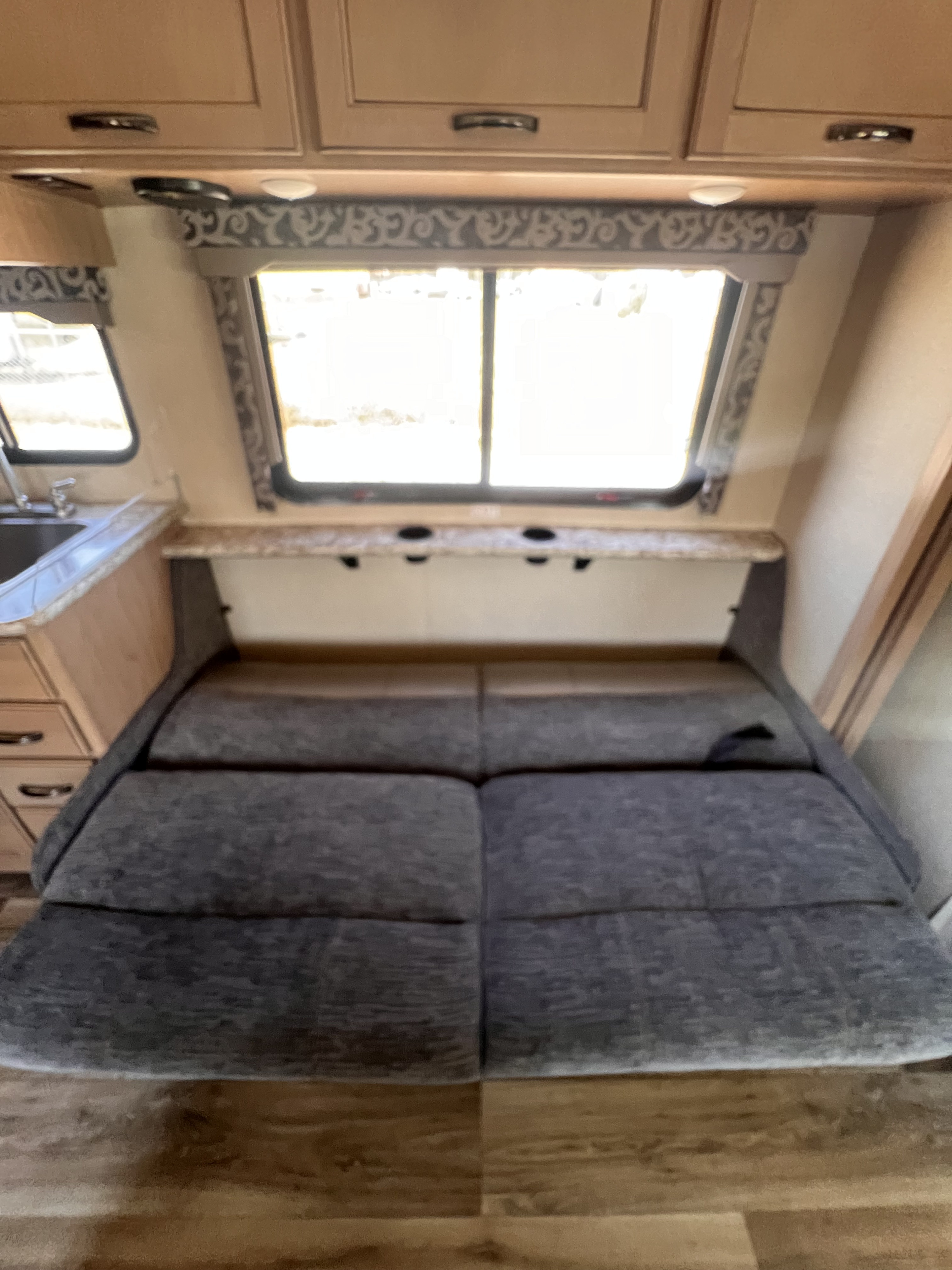 Cozy RV rental interior showing a convertible dinette bed, overhead cabinets, and windows. Perfect for your next adventure.. Thor Four Winds 2019