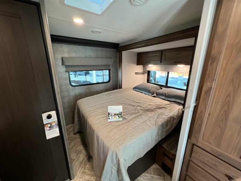 Spacious RV rental bedroom with a comfortable bed, overhead cabinets, and large windows. Perfect for your next road trip!. Forester LE 2022