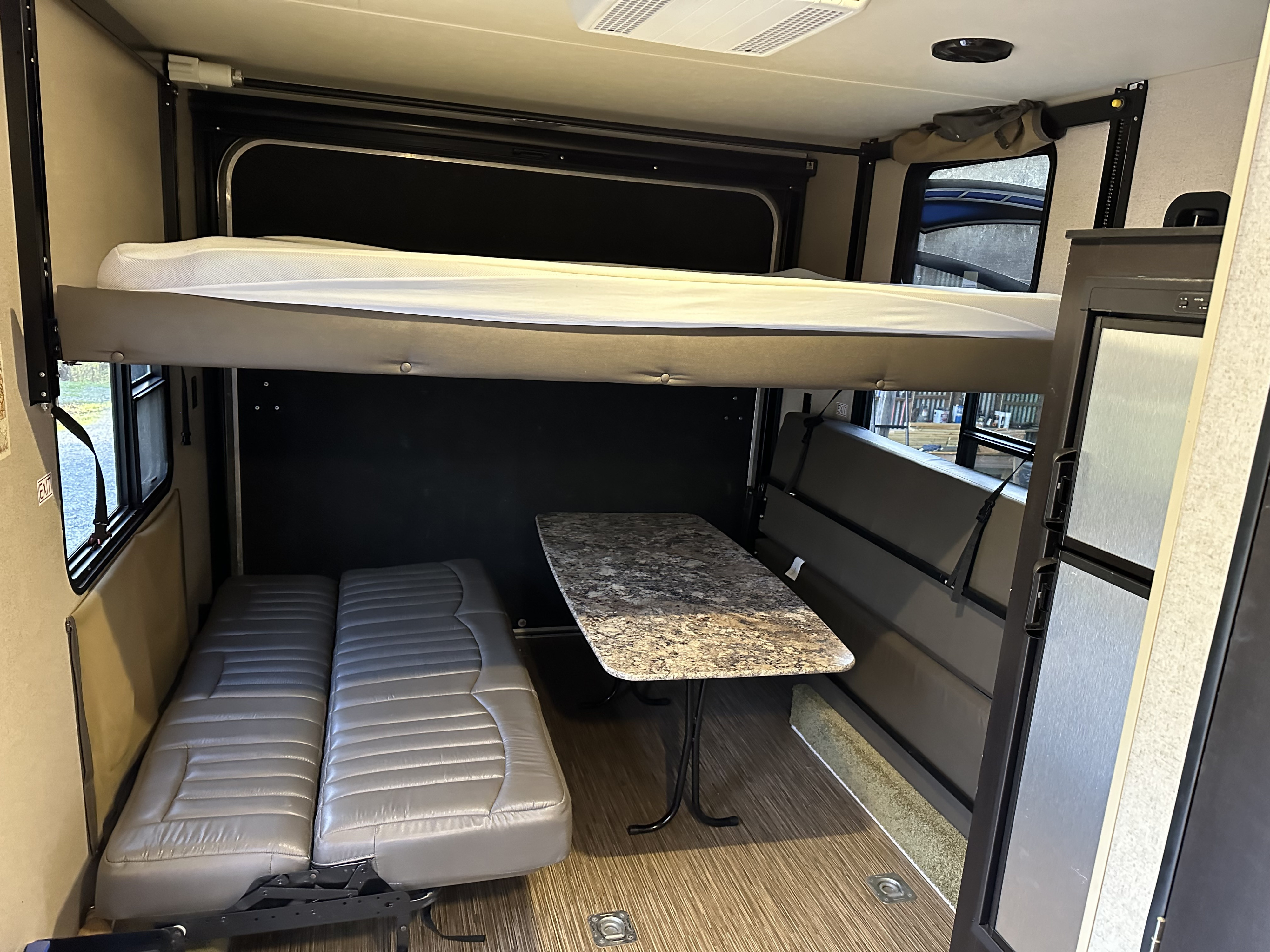 Spacious RV rental interior with bunk bed, convertible seating, dining table, and fridge for comfortable travel.. Jayco Octane 2015