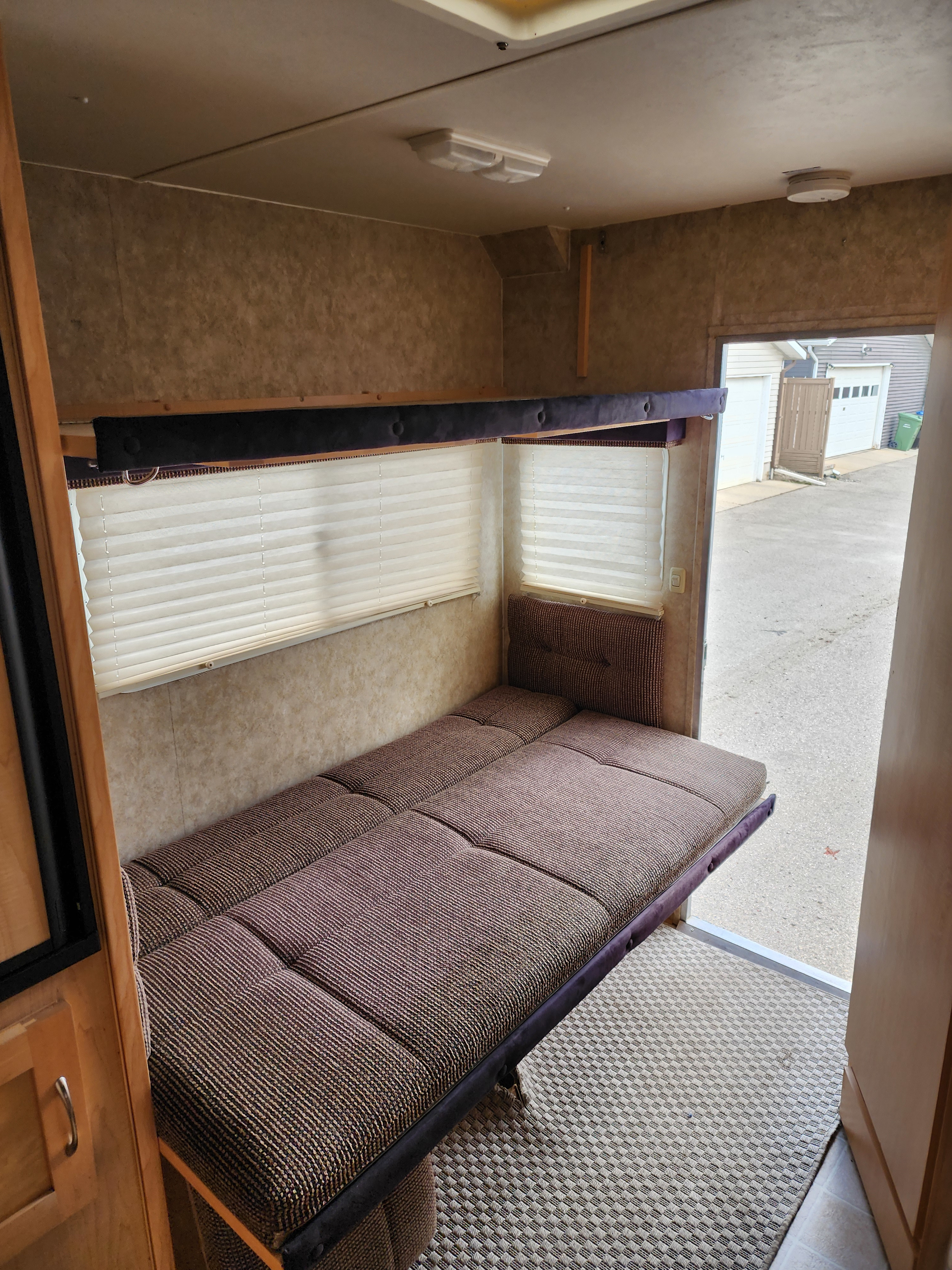 RV rental: Cozy interior featuring a multi-position sofa/bed, overhead bunk, and an open door to the outside.. Ford F350 2012