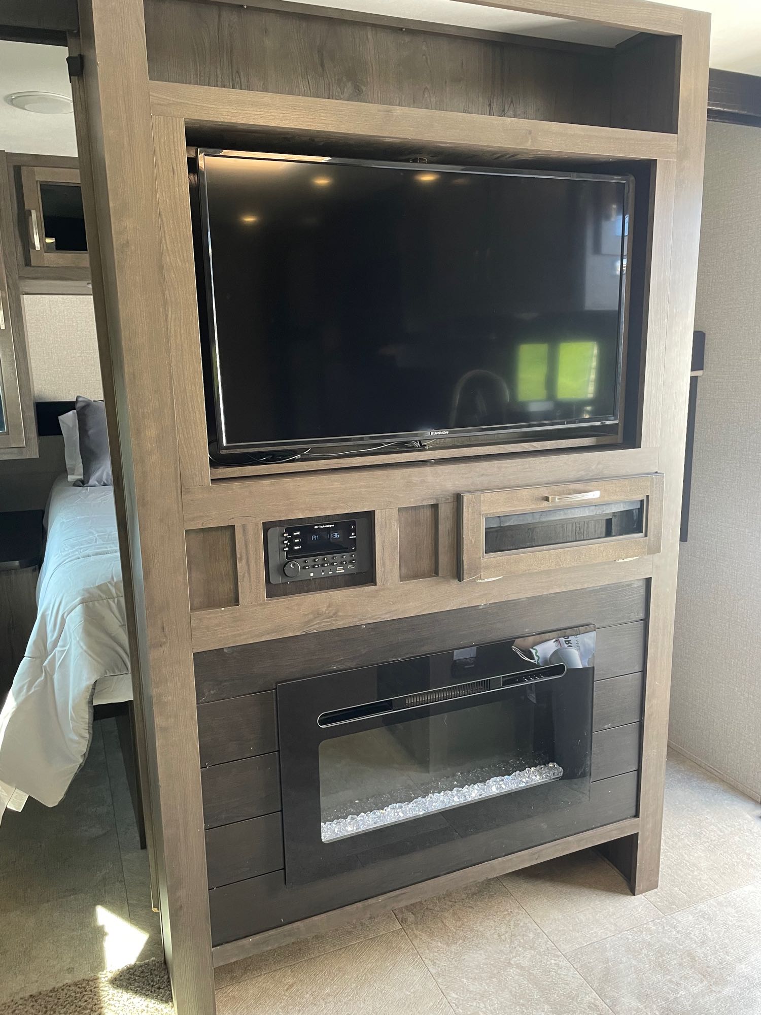 This RV rental features a cozy interior with a built-in entertainment unit (TV, stereo, fireplace) and a bedroom area visible.. Jayco Jay Flight 2020