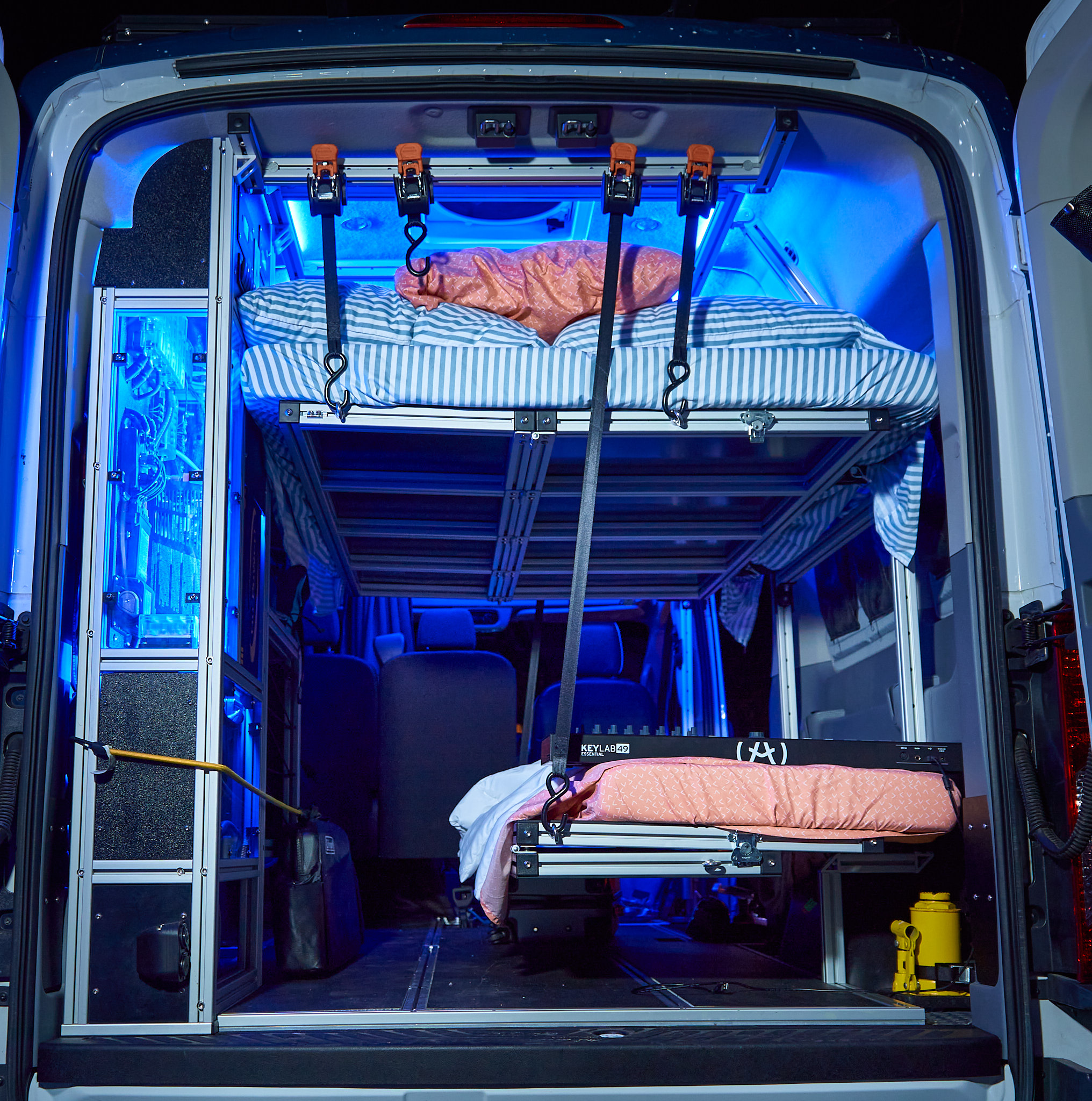 Inside a modern rv rental: custom-built modular bunk beds, bright blue LED lighting, and a mobile creative space for road trips.. Ford Transit 2017