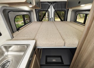 Cozy RV rental camper van interior featuring an elevated bed over storage, a sink, and scenic window views. Great for travel!. Winnebago Solis PX 2025
