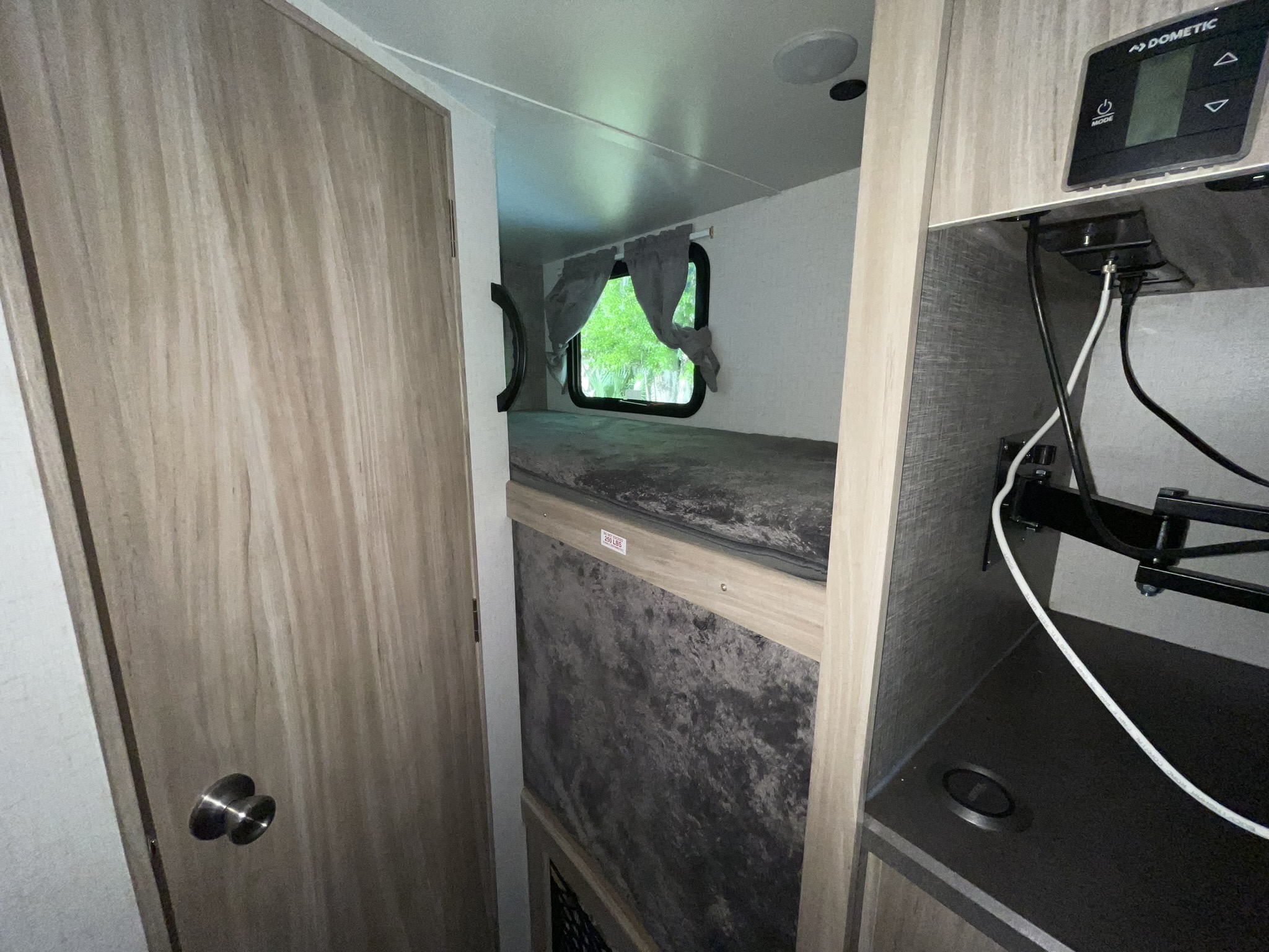 Cozy RV rental interior featuring comfortable bunk beds, a window with curtains, and a Dometic control panel for climate.. Winnebago Minnie Winnie 2022