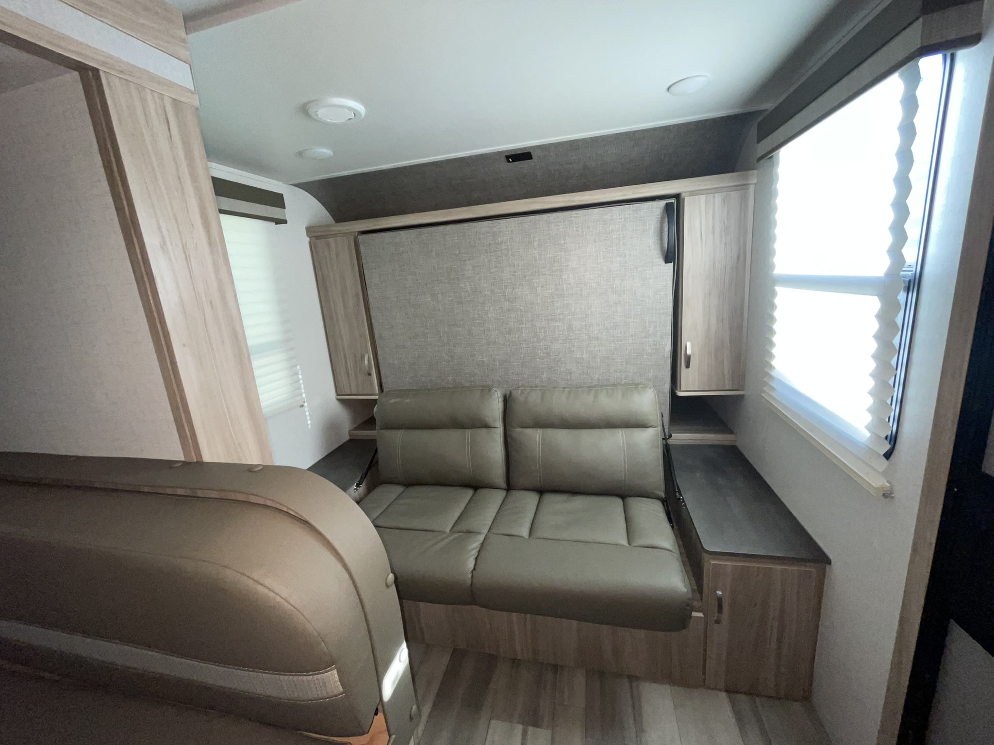 RV rental interior: Sofa transforms into a cozy bed, framed by storage cabinets and a bright window. Ideal compact living.. Winnebago Minnie Winnie 2022
