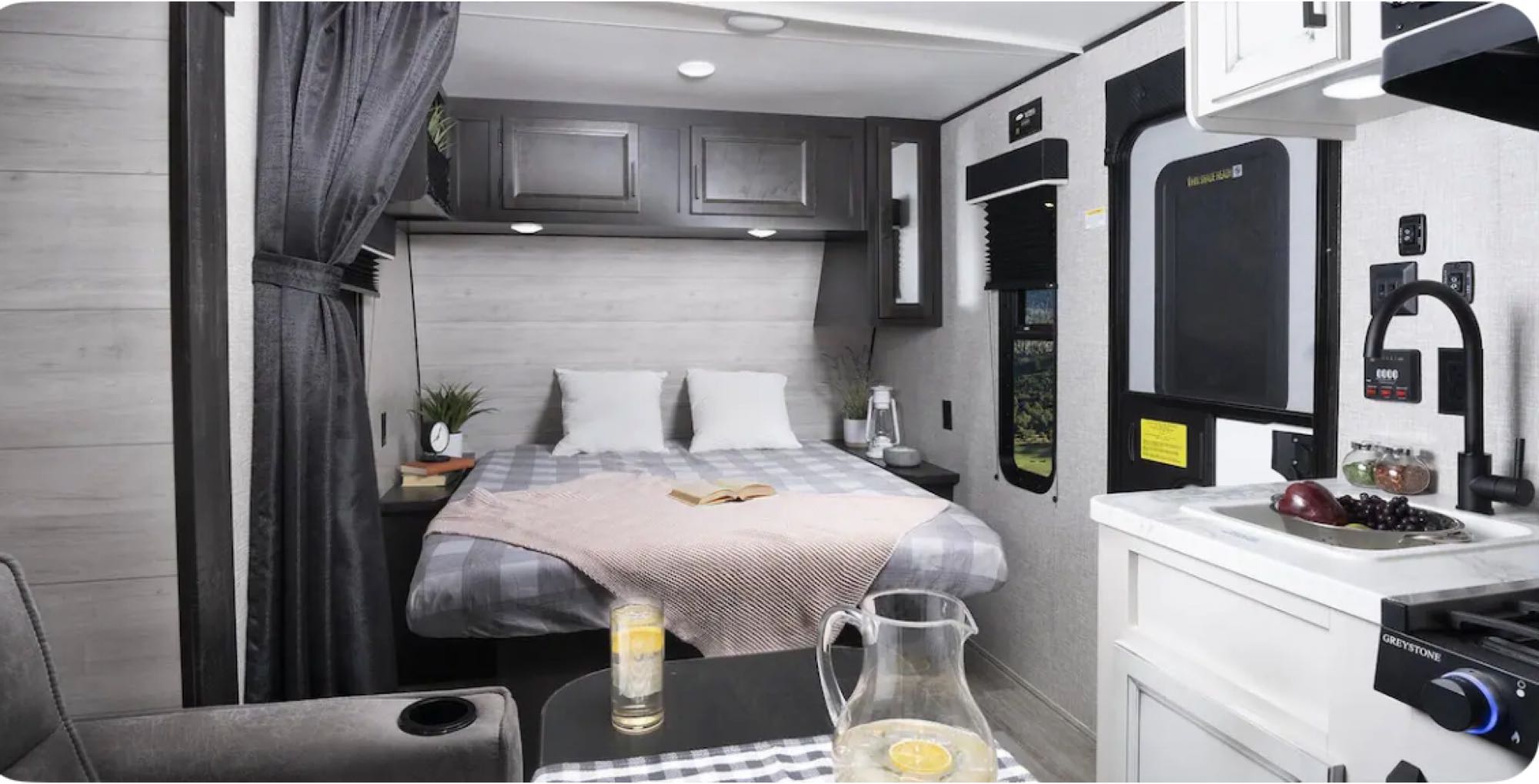 Modern RV rental interior showcasing a cozy bed, functional kitchen with sink & stove, and dining space.. Jayco Jayflight 2024