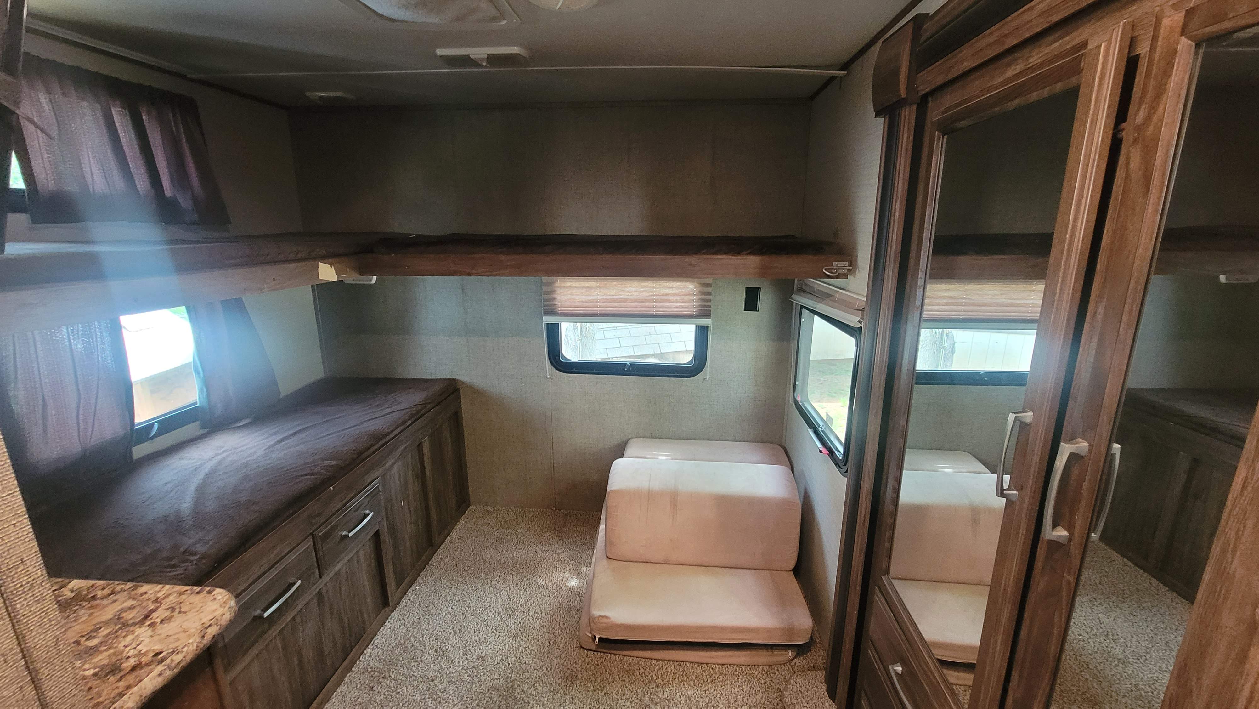 RV rental interior shows bunk beds, a folding mattress, and a mirrored cabinet, providing diverse sleeping arrangements.. Keystone RV Cougar 2017