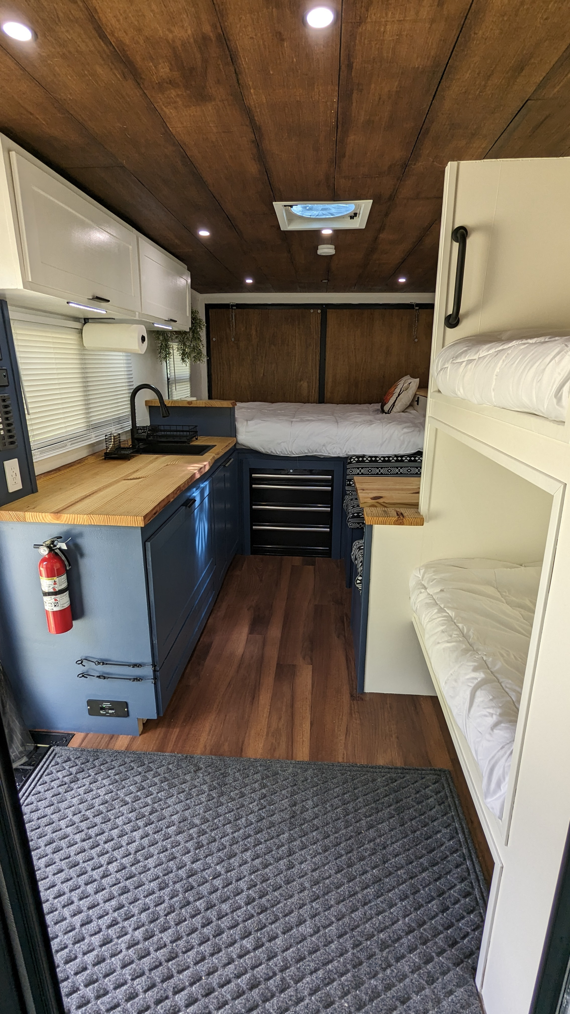 RV rental: Cozy camper van interior with a full kitchen, bed, and bunk beds, featuring a wooden ceiling.. Diamond Cargo 16x8.5 2023